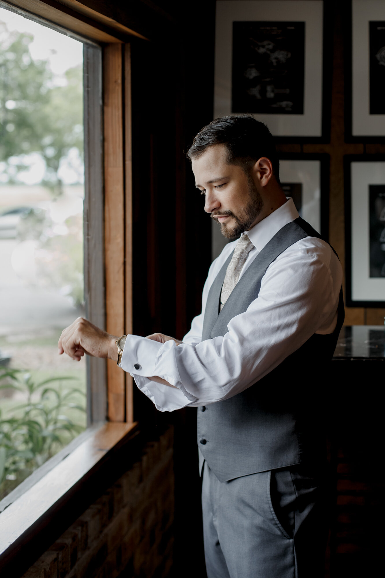 Groom getting ready by the window. Glowing Wedding in Golden Champagne Tones at The Orchard at Caney Creek in Wharton, TX
