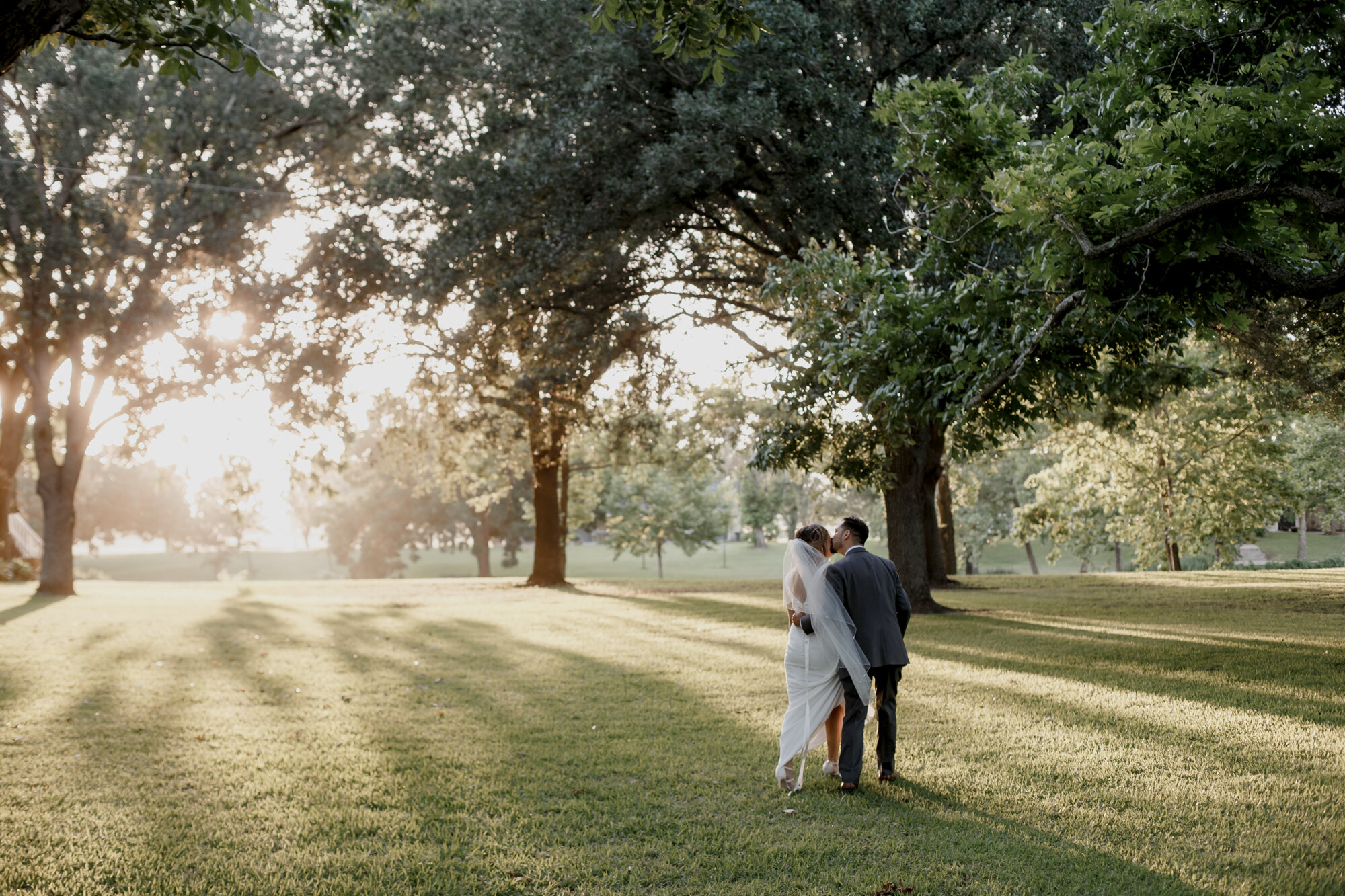 Bride and groom walk away in the sunset. Glowing Wedding in Golden Champagne Tones at The Orchard at Caney Creek in Wharton, TX