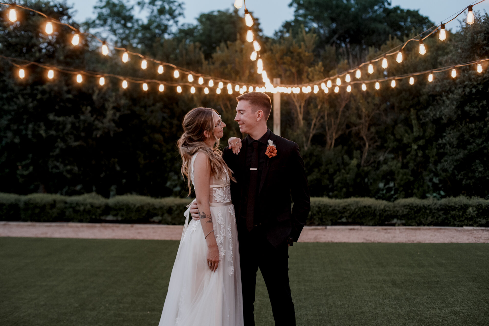 Bride and groom portrait with string lights. Burnt Orange and Black Fall Wedding at The Farmhouse