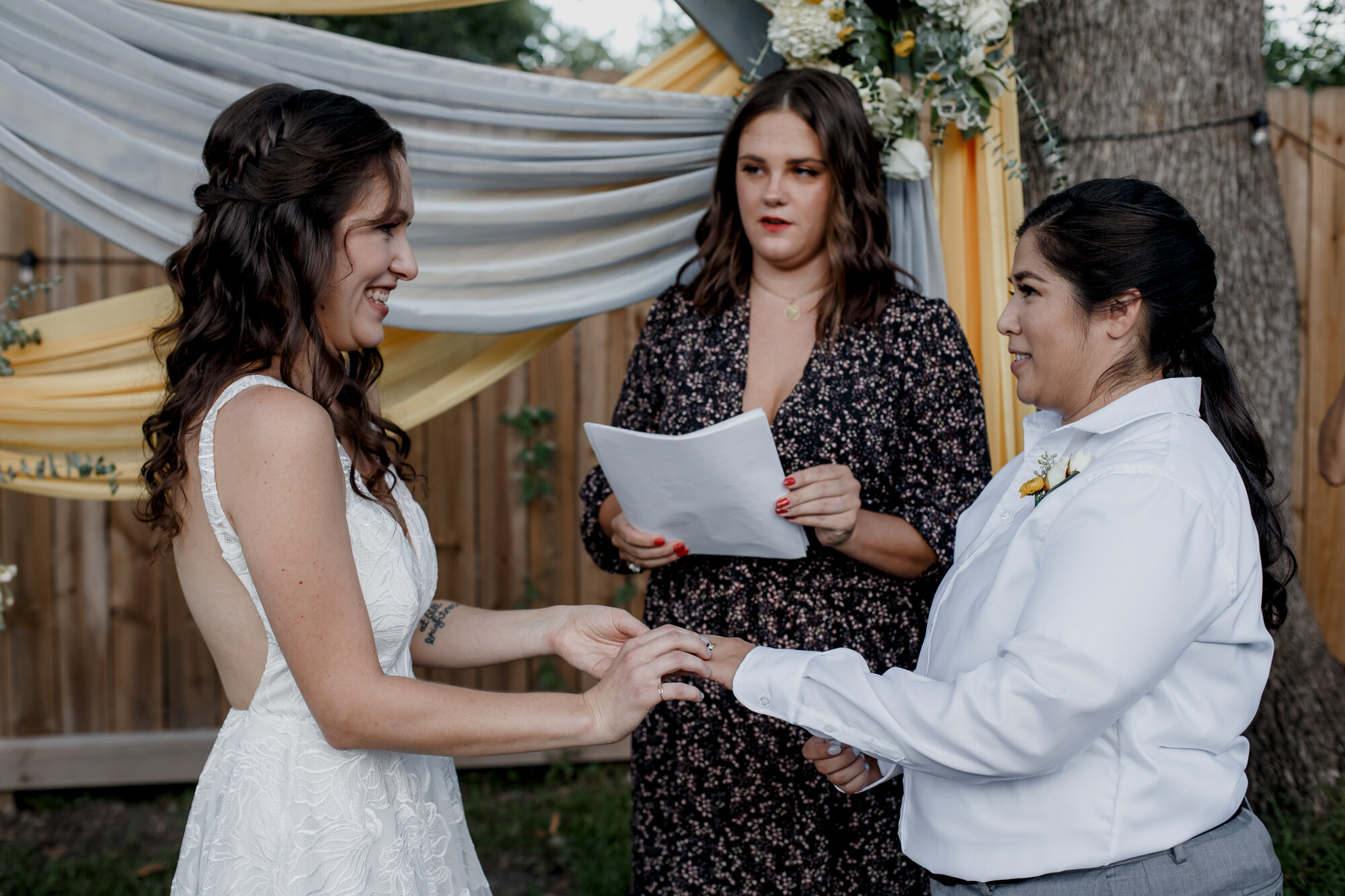 Cozy Laid-Back LGBTQ+ Backyard Wedding Ceremony, brides, partners exchange rings.