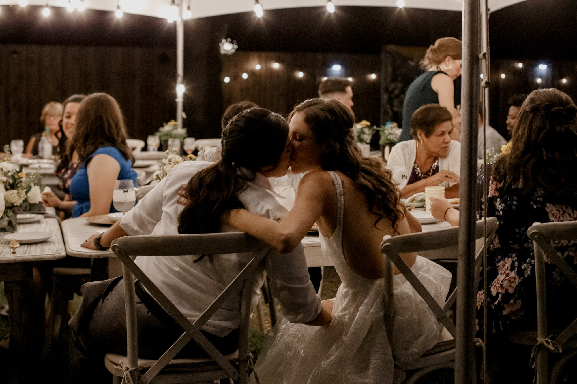 Cozy Laid-Back LGBTQ+ Backyard Wedding. Brides kiss at the night time receptionLGBTQ+ Backyard Wedding (Houston, TX)