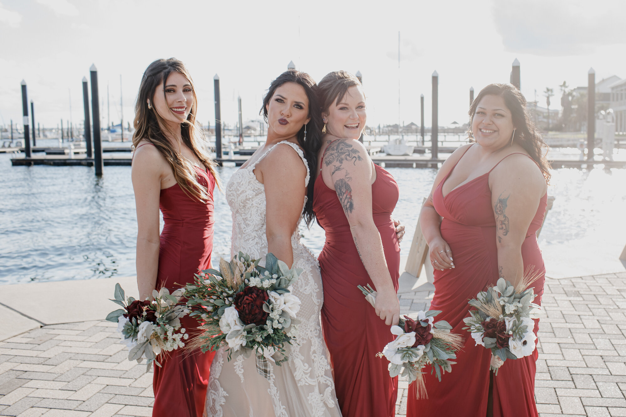 Bride and bridesmaids wearing red dresses. Fun and Glowing Wedding at Sea Star Base