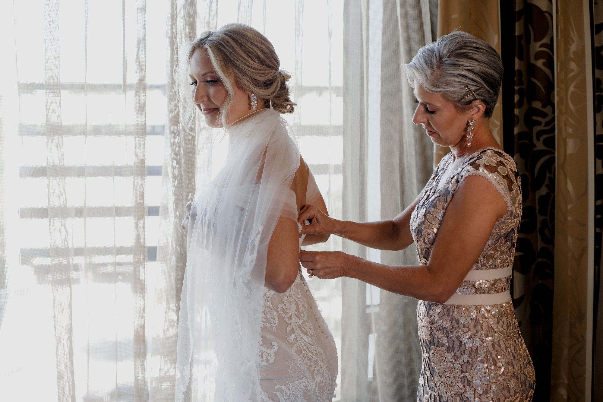 Mother zipping bride's dress. Elegant and Glamorous Uptown Wedding at Omni Houston Hotel and The Wynden