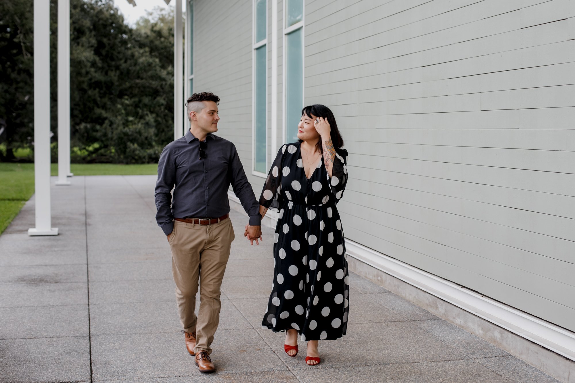 Couple walking holding hands - Stylish Polka Dot Dress Engagement Photo Session at Menil Park