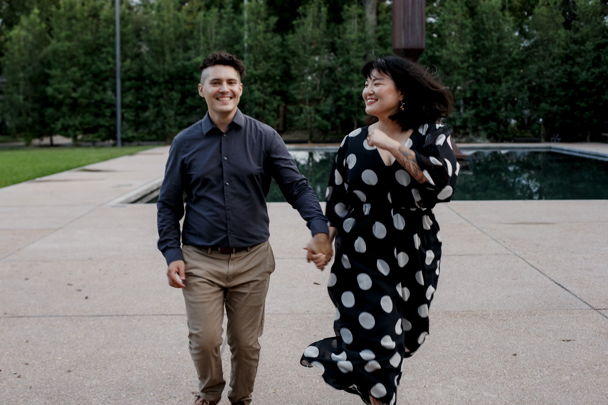 Couple runs laughing. Stylish Polka Dot Dress Engagement Photo Session by Rothko Chapel Sculpture