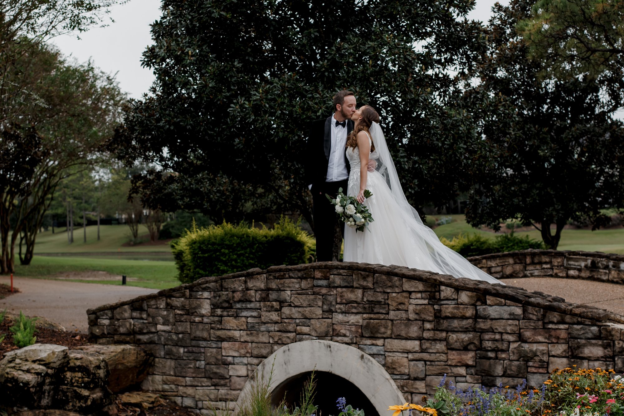 Bride and groom kissing on a bridge. Wedding at Royal Oaks Country Club