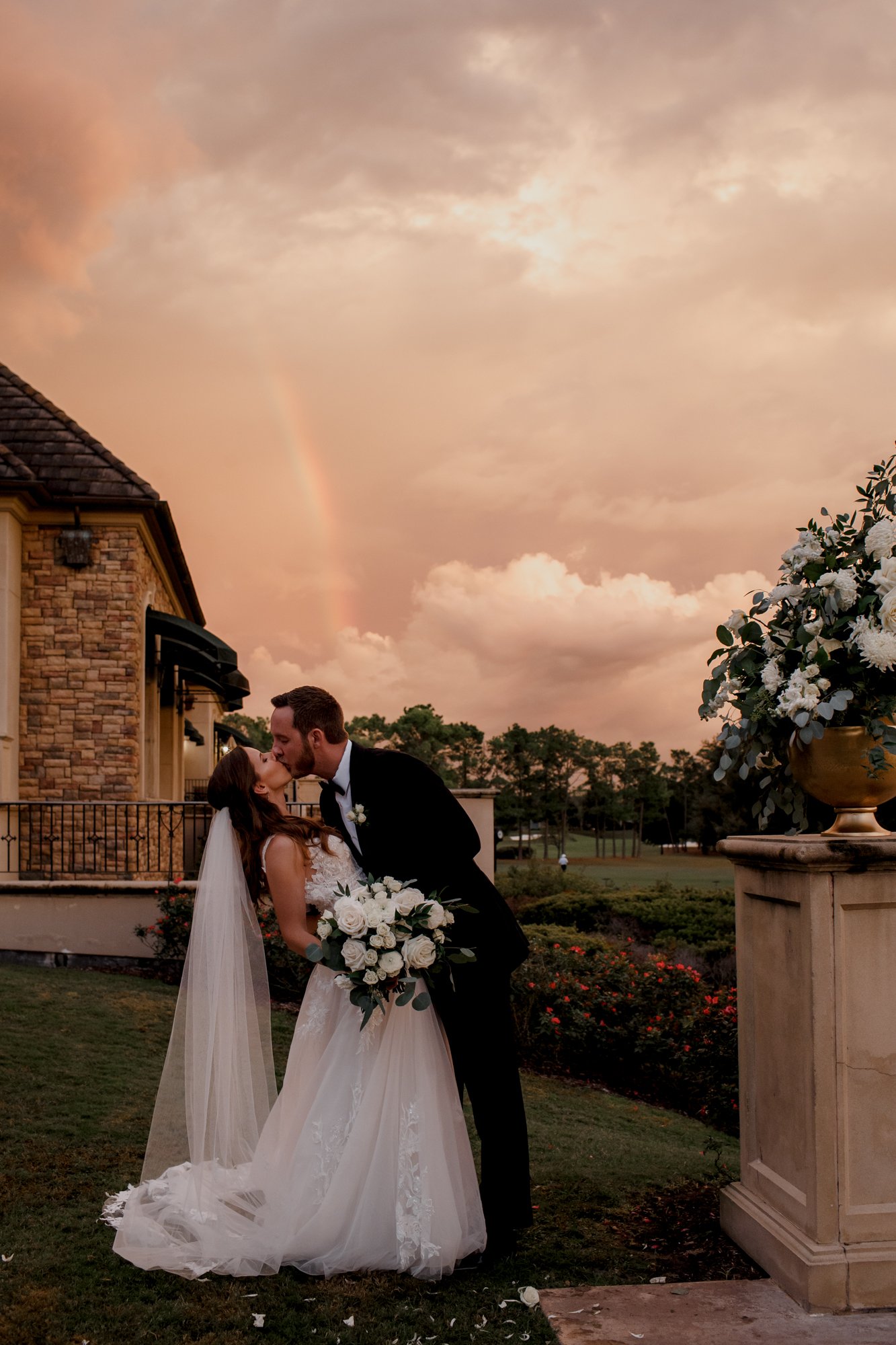 Bride and groom kiss with a rainbow on a background. Wedding at Royal Oaks Country Club