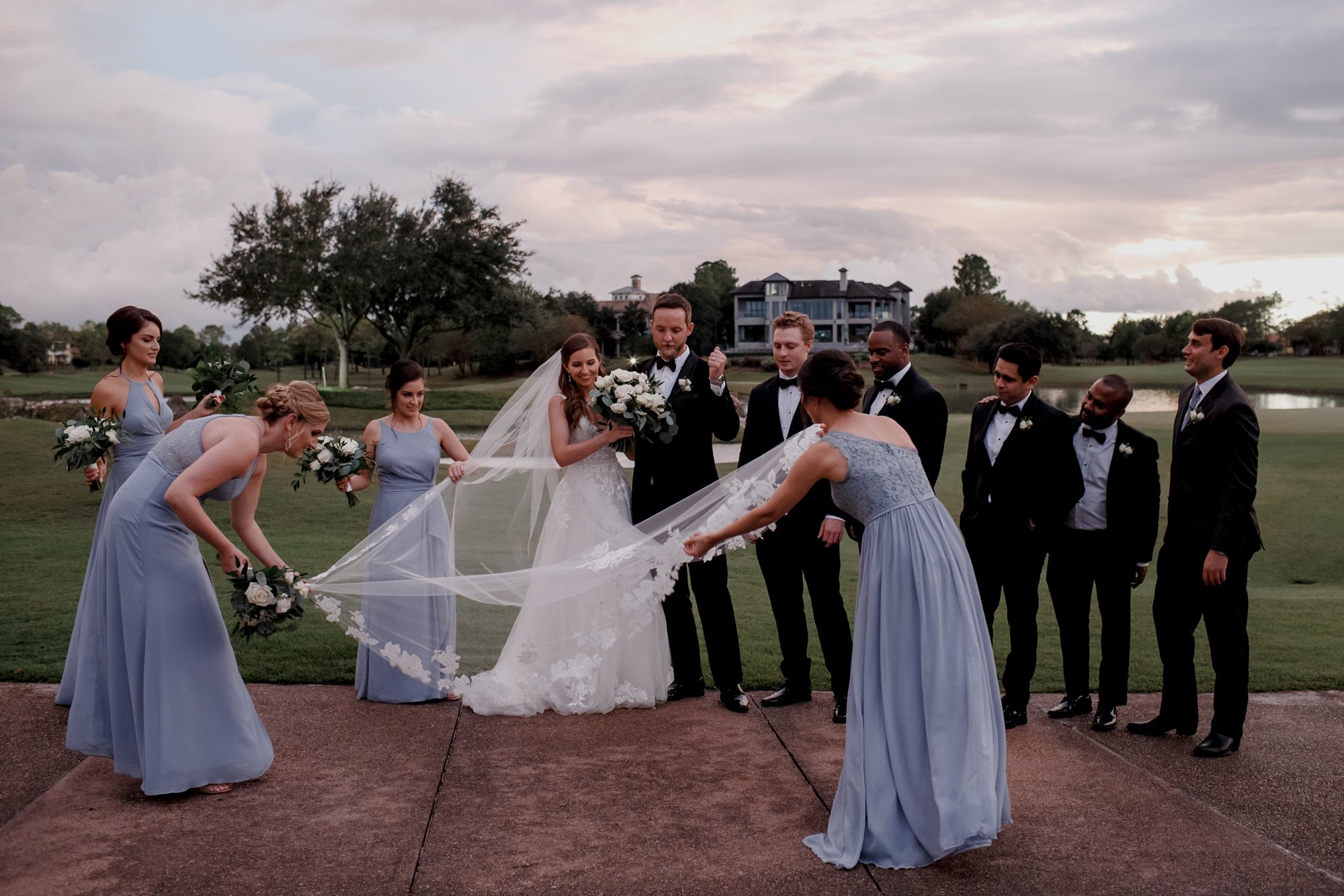 Bridesmaids arrange bride's veil. Wedding at Royal Oaks Country Club