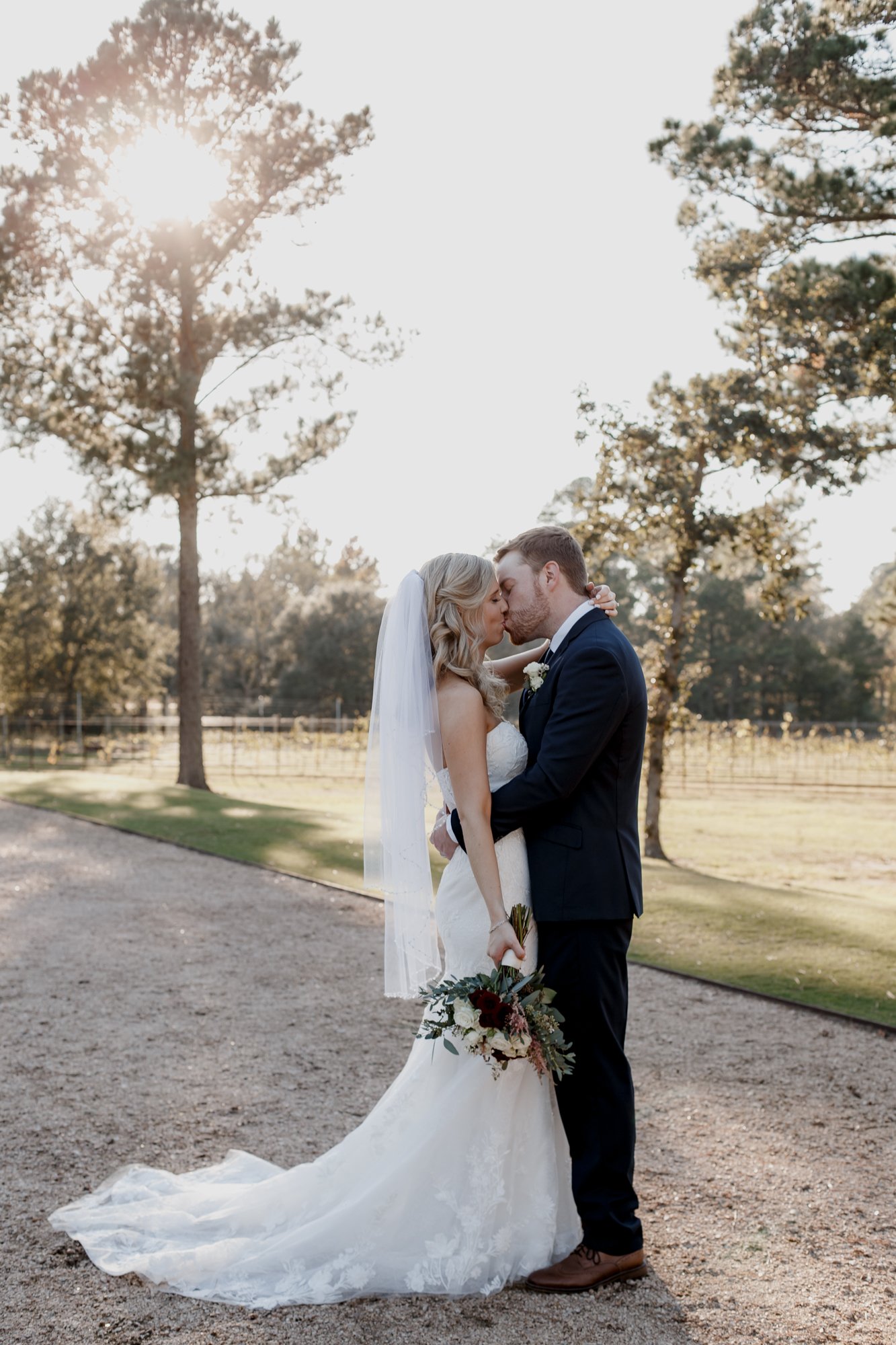 Bride and groom kiss in sunlight - golden hour sunset portraits. Wedding at The Vine (New Ulm, TX)