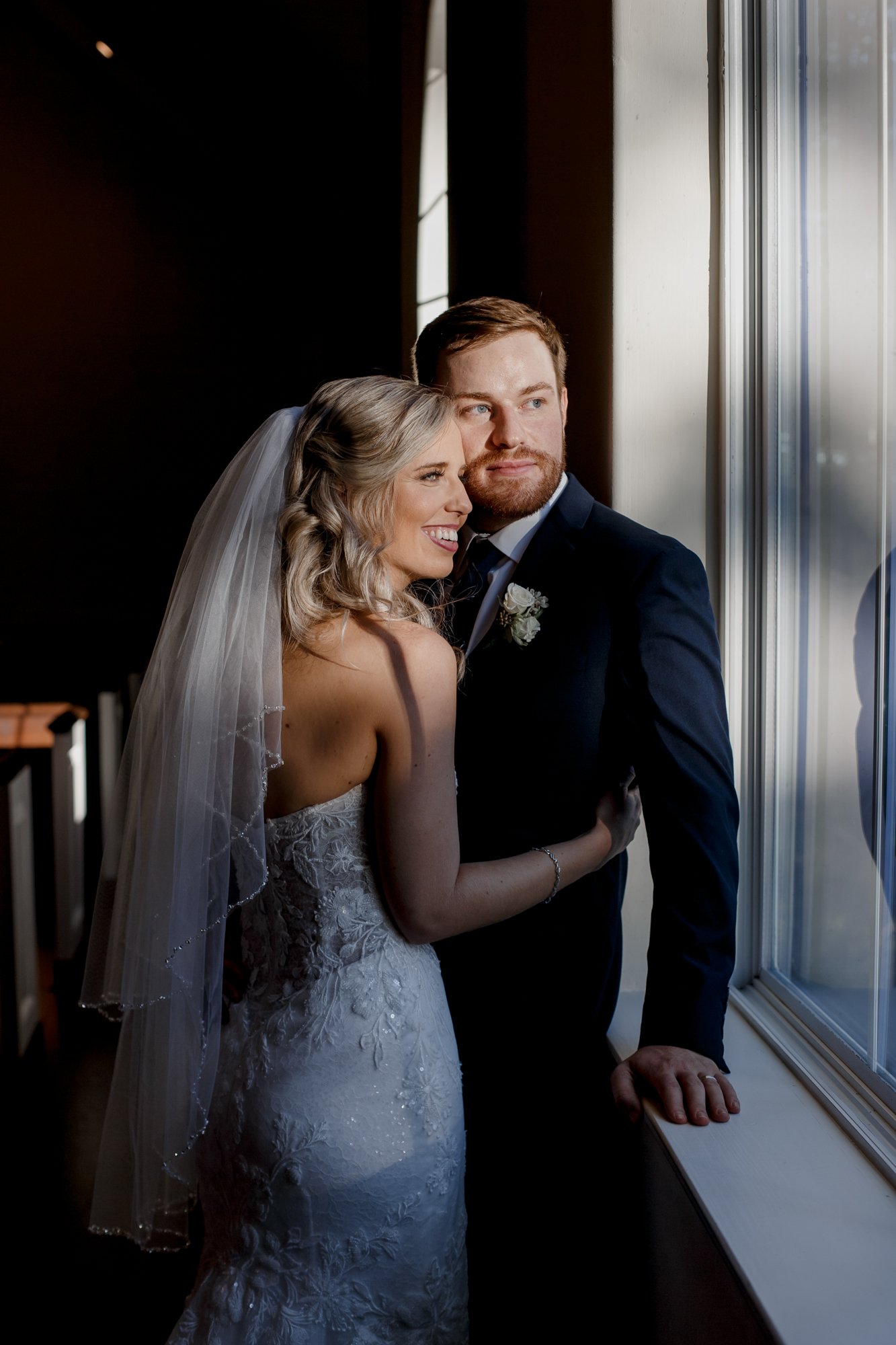 Bride and groom moody portraits in the chapel by the window. Wedding at The Vine (New Ulm, TX)