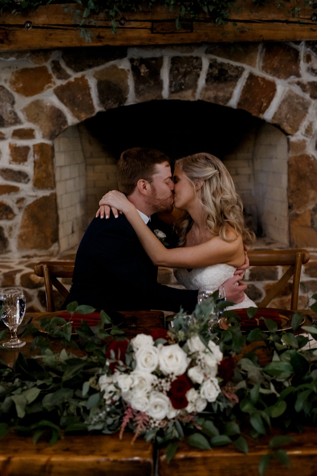 Bride and groom kissing at the sweetheart table. Wedding at The Vine (New Ulm, TX)