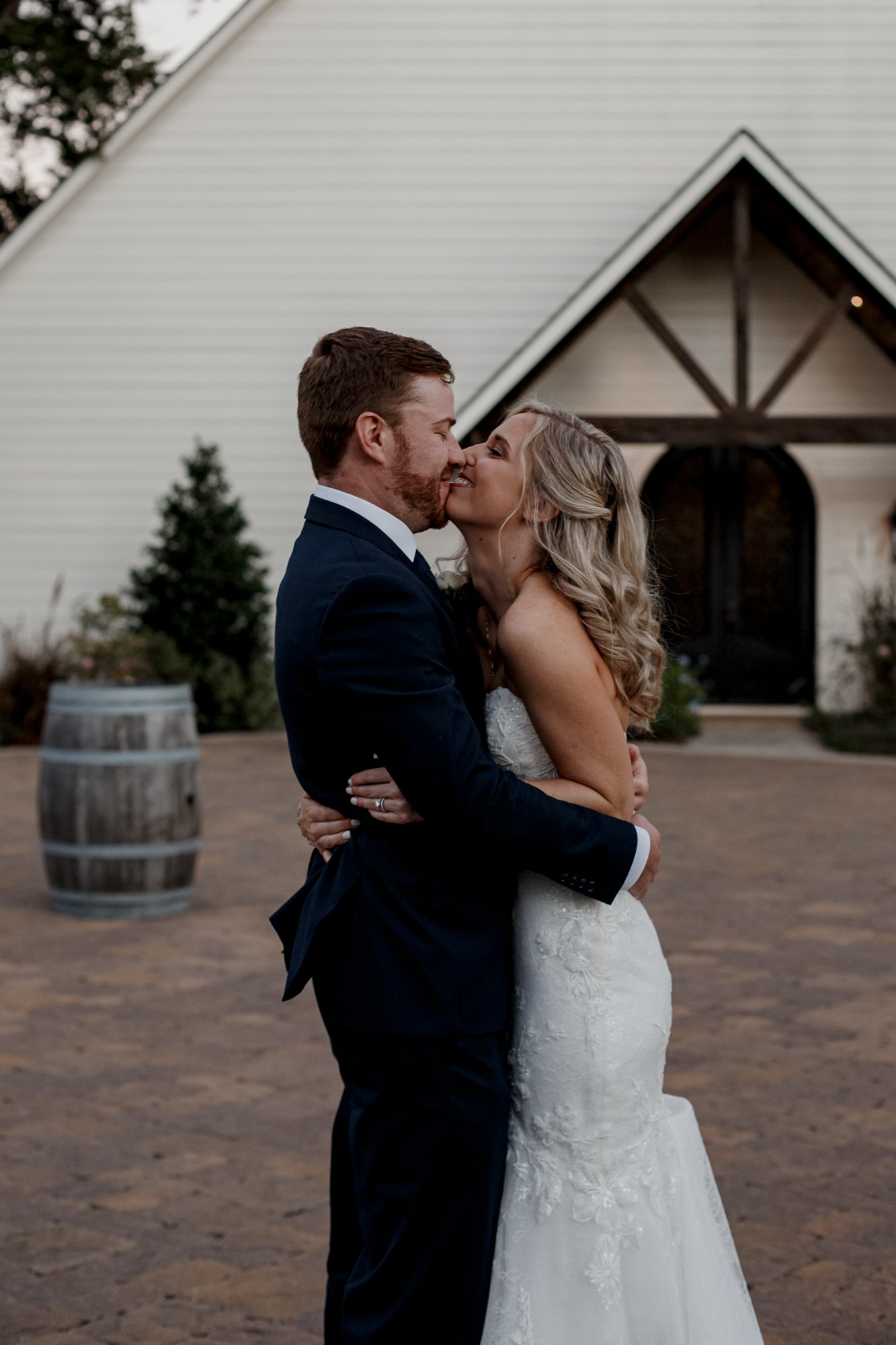 Bride and groom kiss outside the chapel. Wedding at The Vine (New Ulm, TX)