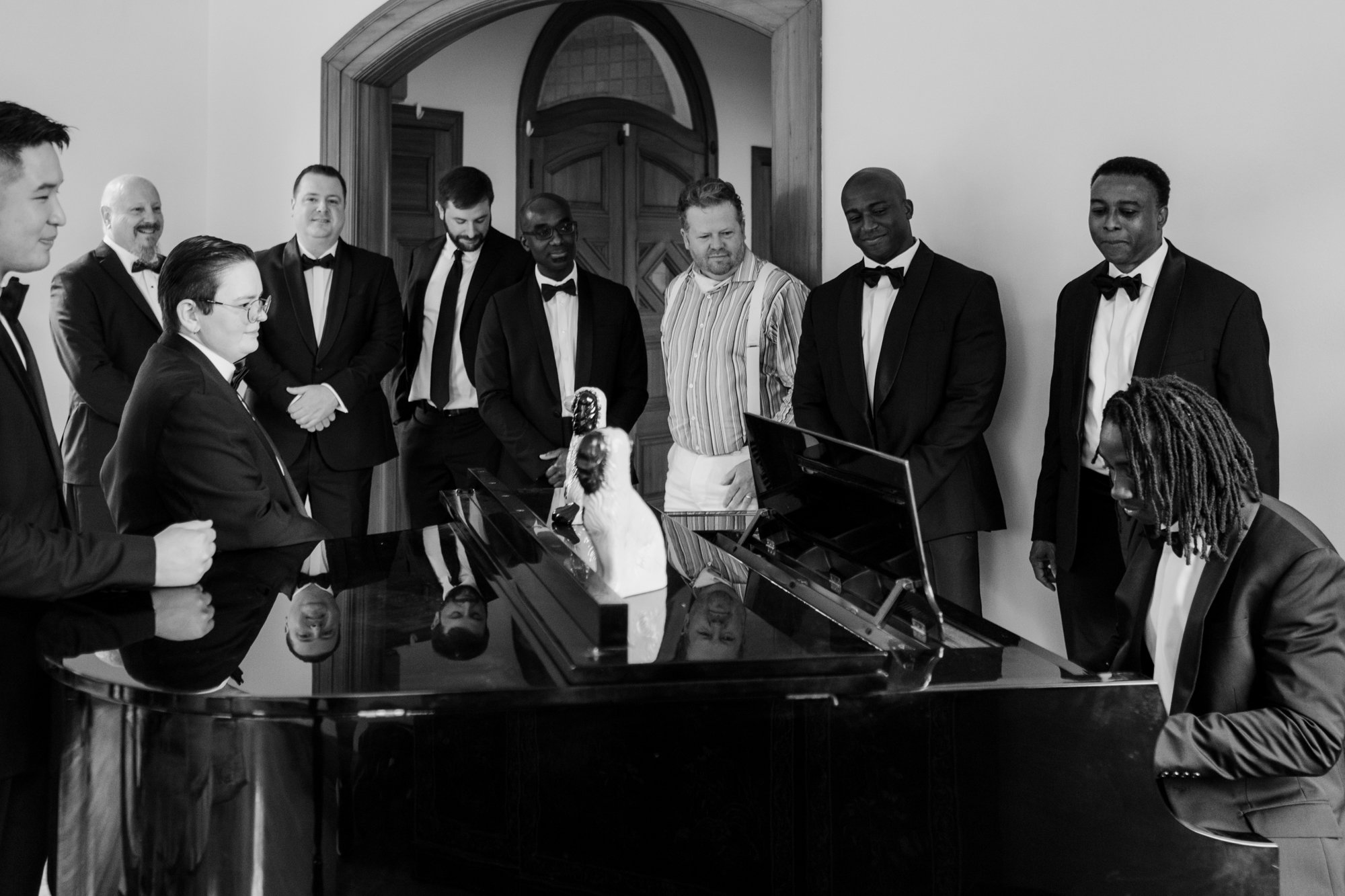 Private house preparations groom plays piano with groomsmen standing behind. New Orleans Style Wedding at McGovern Centennial Gardens