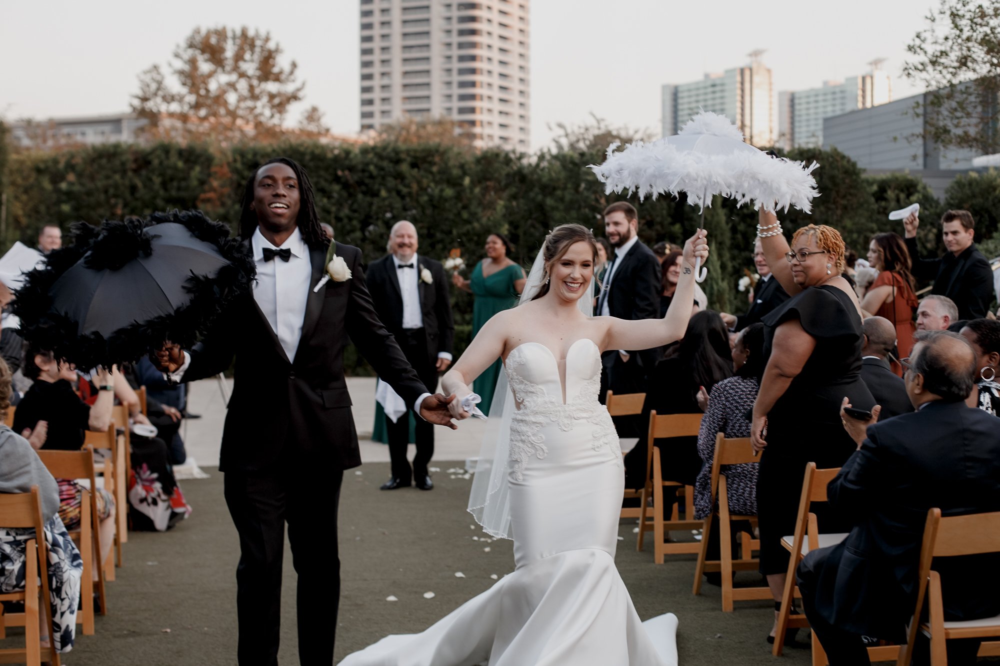 Bride an groom walking down the aisle with umbrellas. New Orleans Style Wedding at McGovern Centennial Gardens