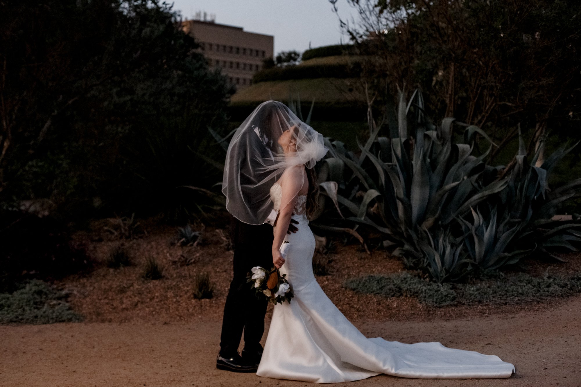 Bride and groom under veil kiss Wedding at McGovern Centennial Gardens