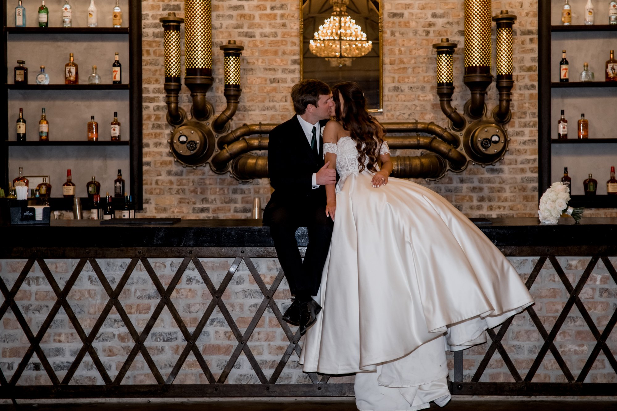 Bride and groom sitting on a bar. Wedding at Iron Manor (Montgomery, TX)
