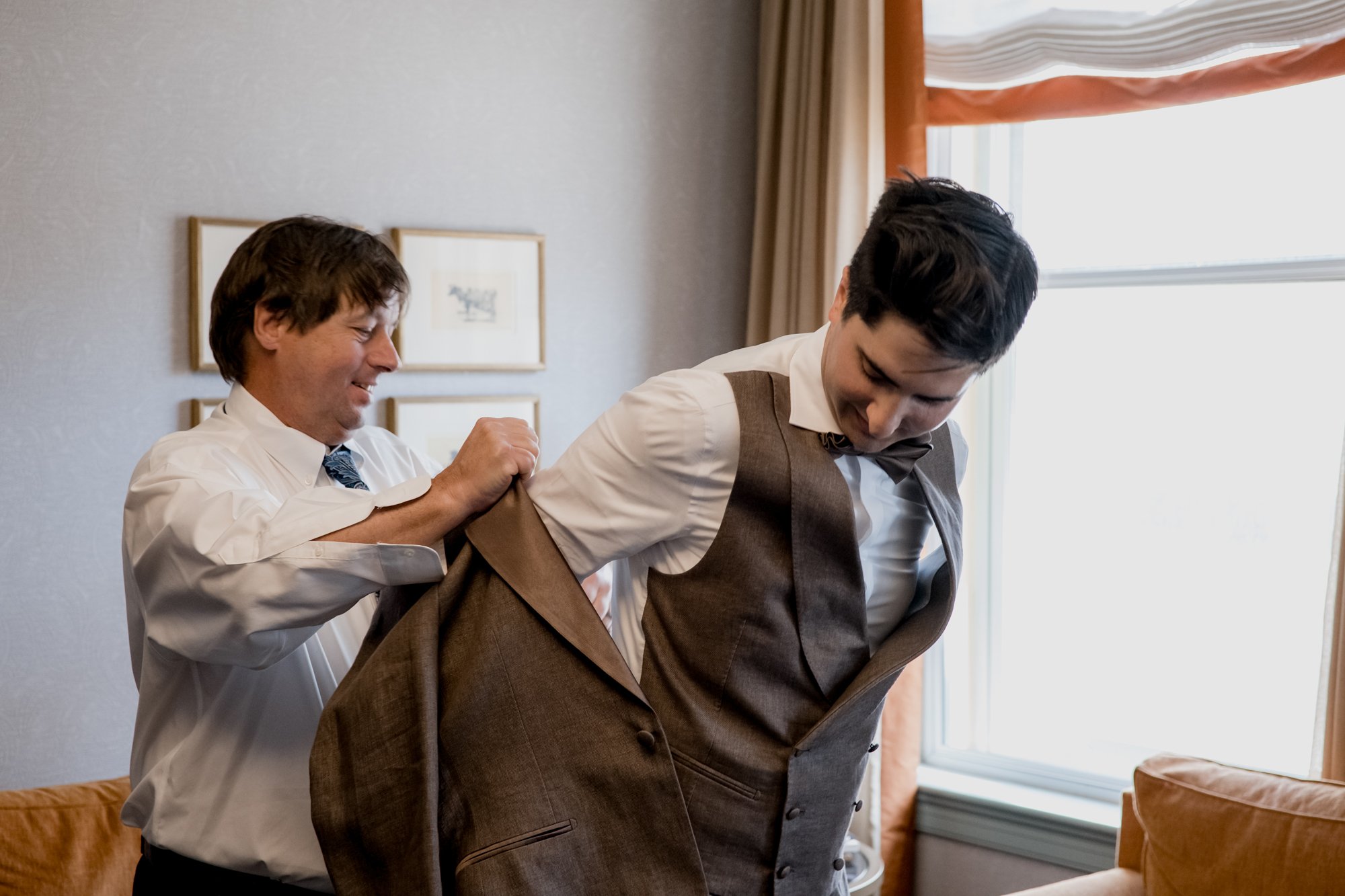 Groom preparations getting ready putting jacket on. Wedding at Hotel Icon
