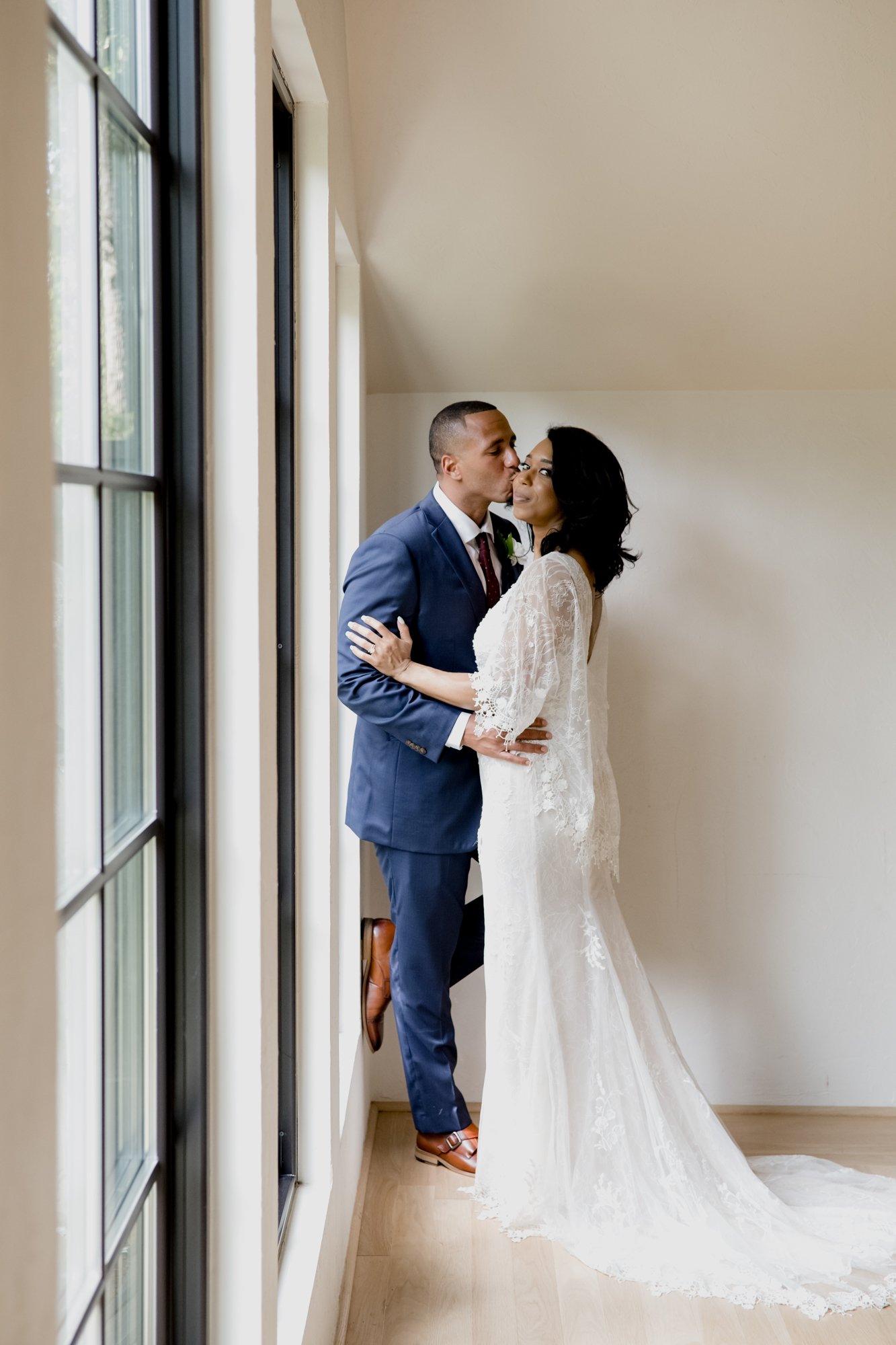 Bride and groom kissing by the window. Wedding at The Oak Atelier