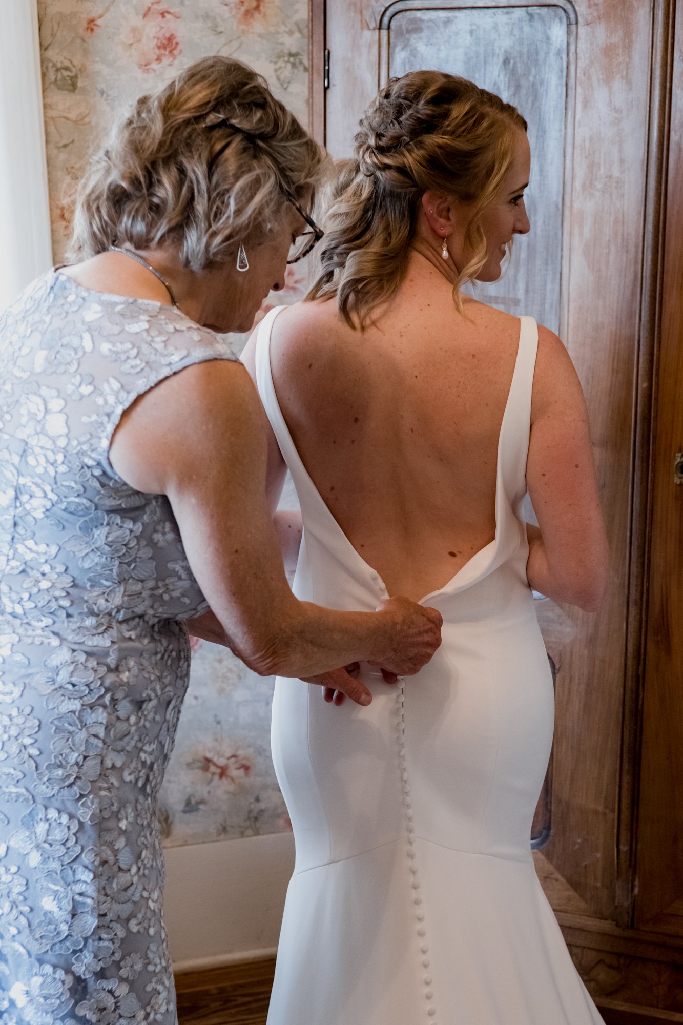 Mother zipping bride's dress. Wedding at Antique Rose Emporium