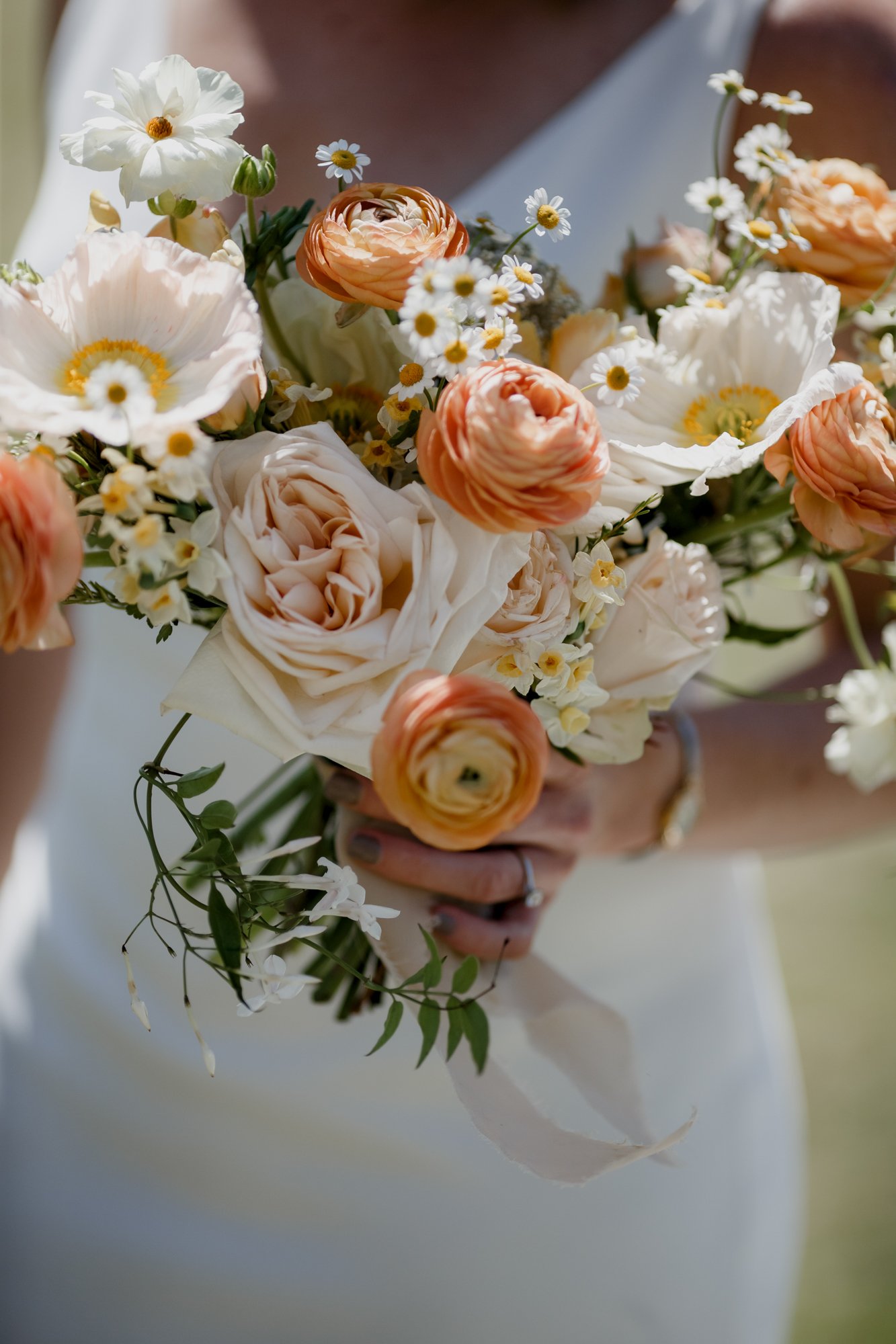 Bride holds her colorful golden tones bouquet. Wedding at Antique Rose Emporium