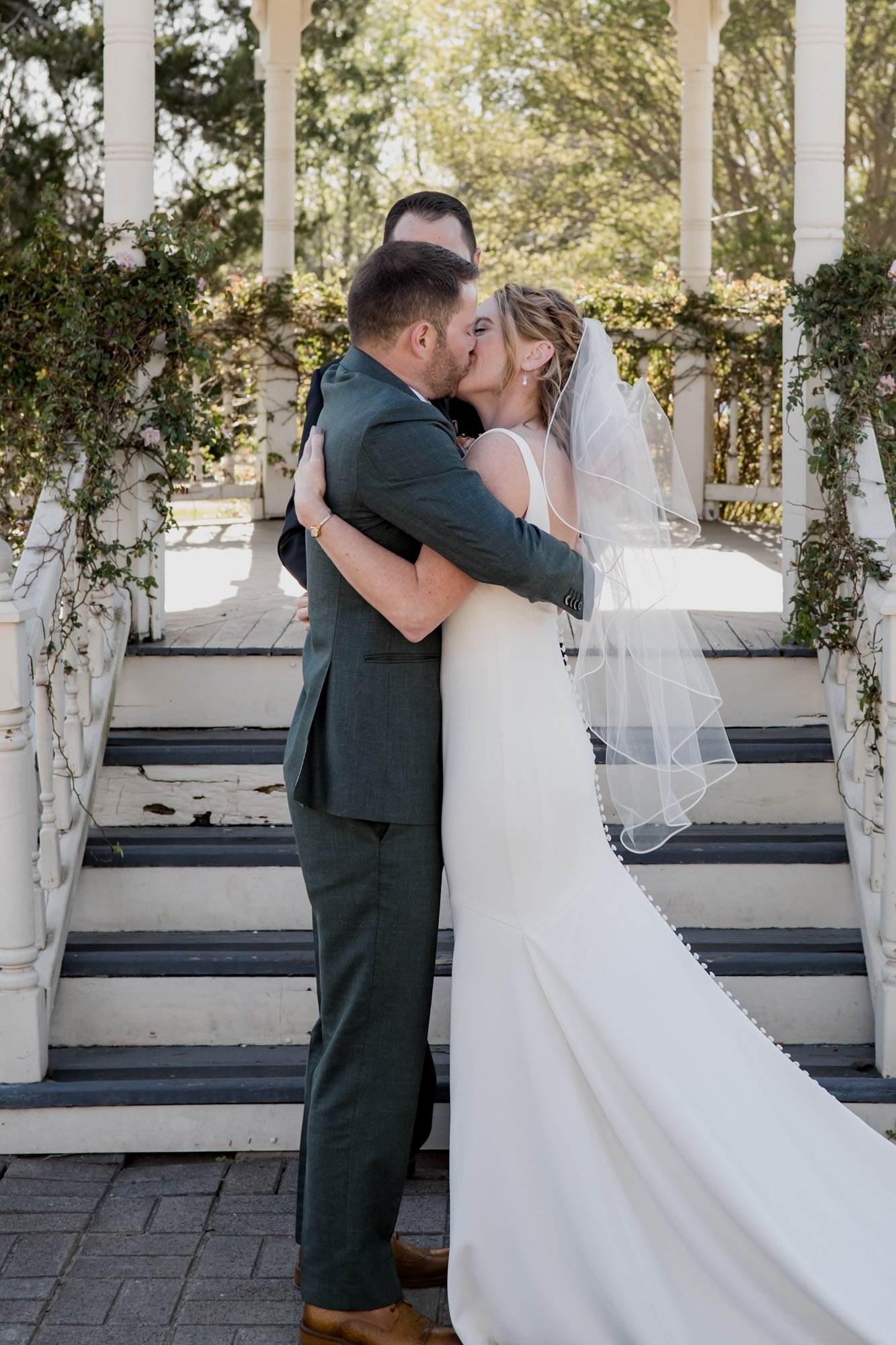 Bride and groom share first kiss - Wedding at Antique Rose Emporium