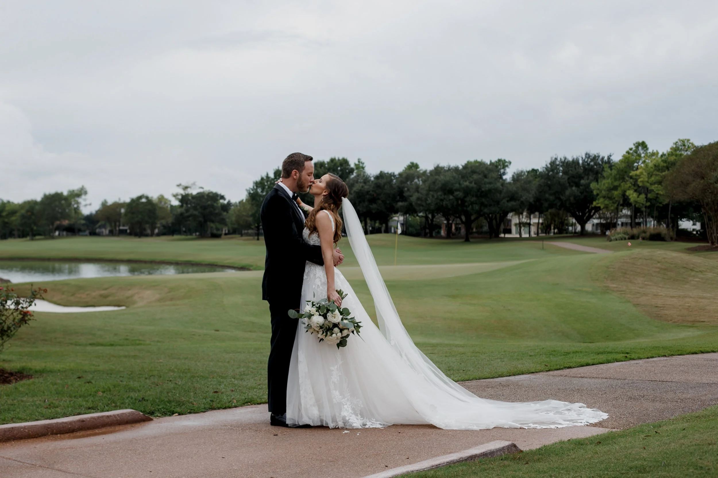 bride and groom kissing overlooking golf course