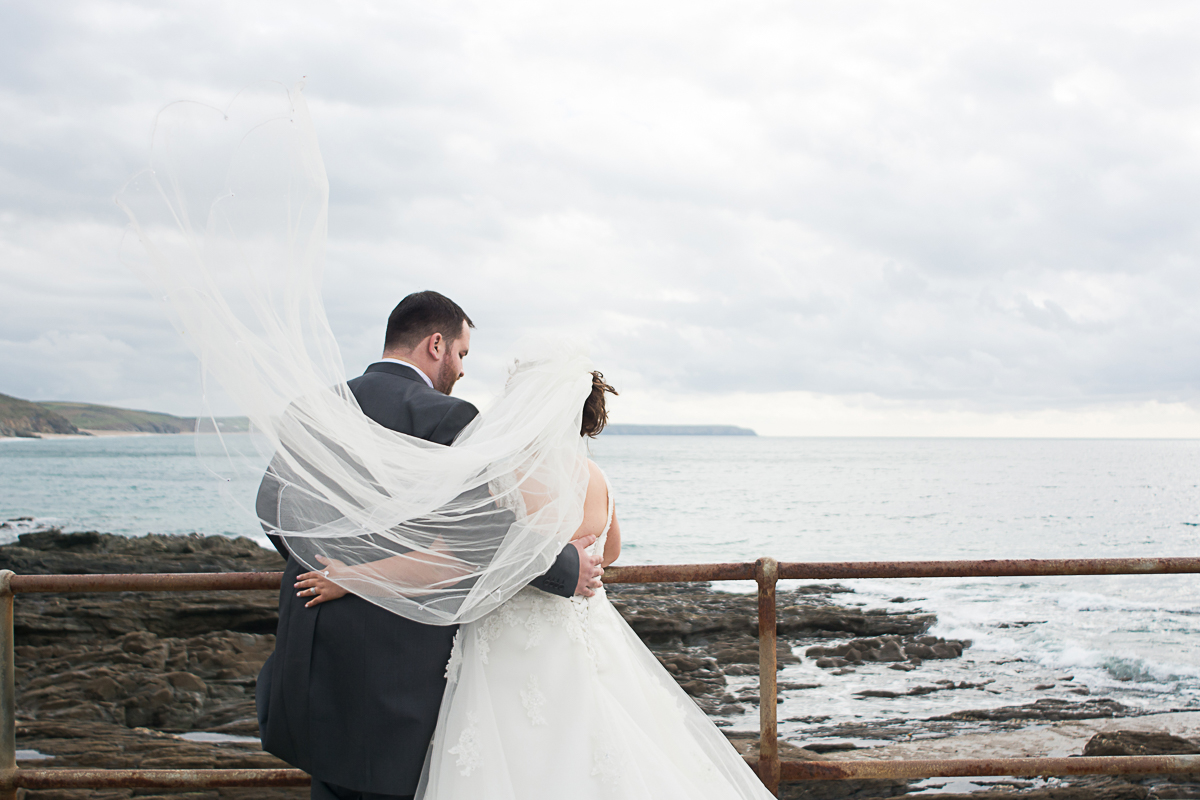 bride and groom look out to sea in porthleven