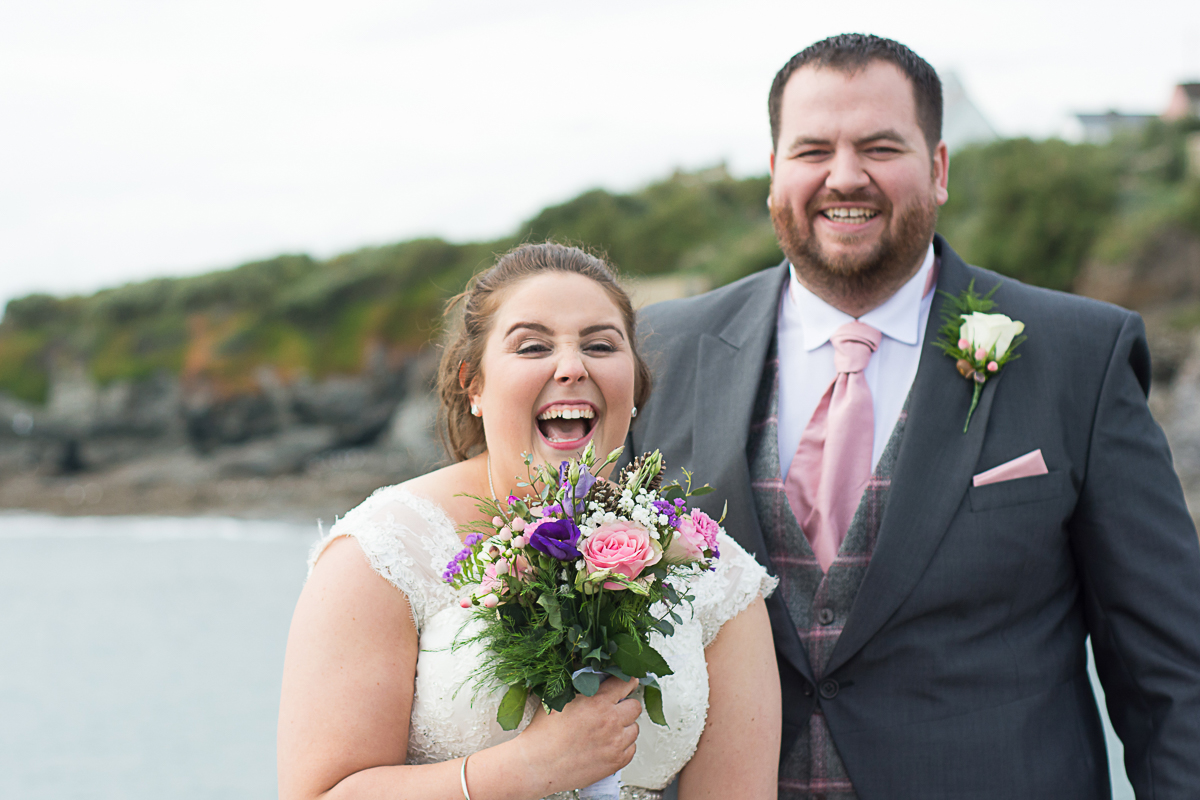 belly laughing bride and groom on Porthleven pier