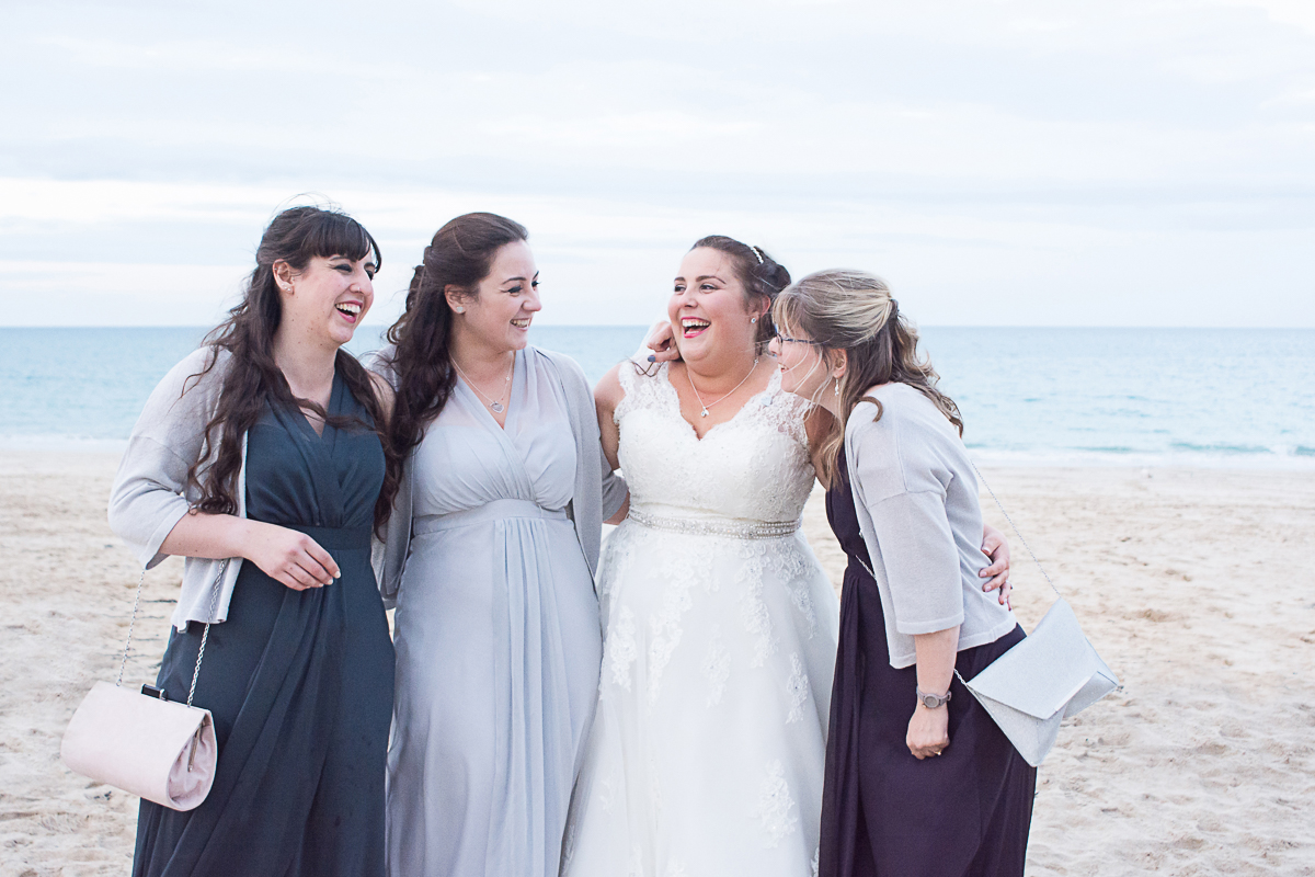 bride and bridesmaids laughing on carbis bay beach cornwall