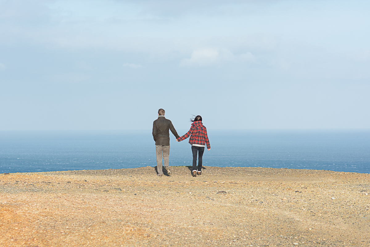 engaged couple hold hands and look at the sea in St Agnes Cornwall