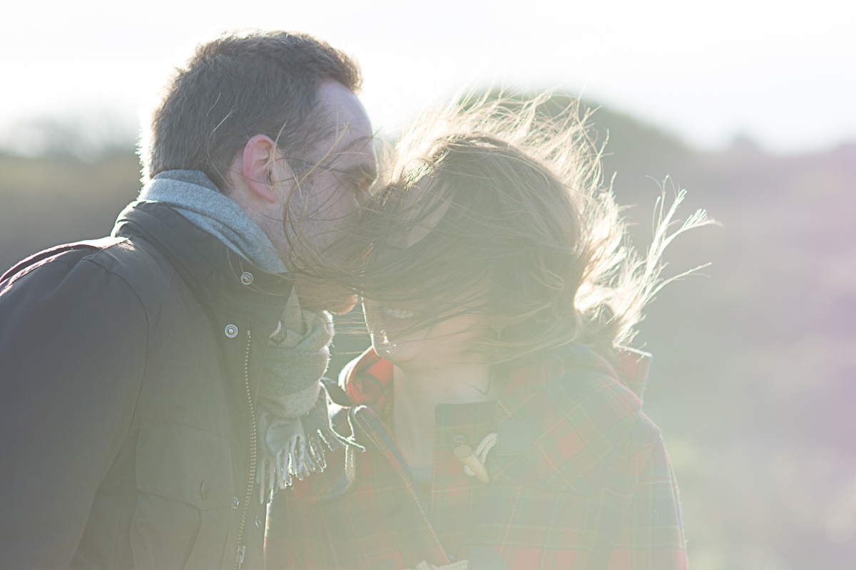 wind blows in her face as he kisses her cheek in st agnes cornwall