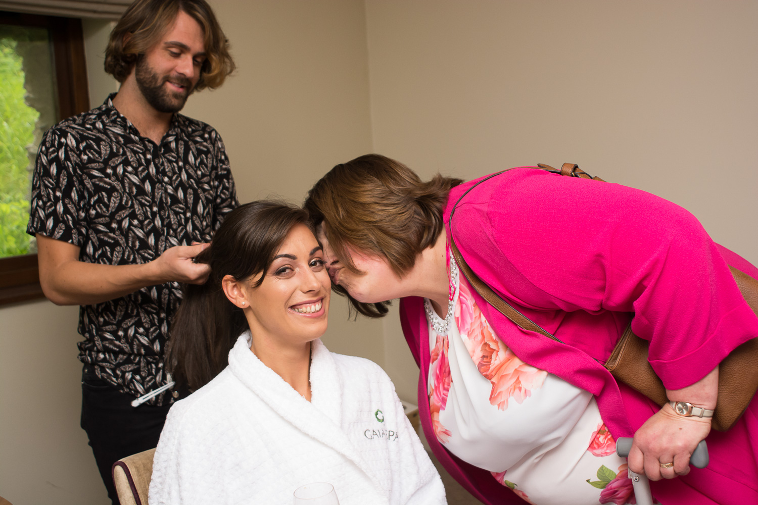 Brides mum gives her a big kiss whilst bride has her hair done by Adam James Hairstylist at Boringdon Hall