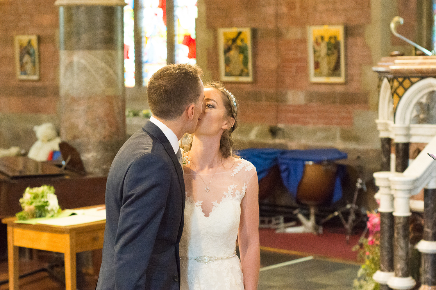 the bride and groom have their first kiss at All Saints Church Babbacombe, Torquay, Devon