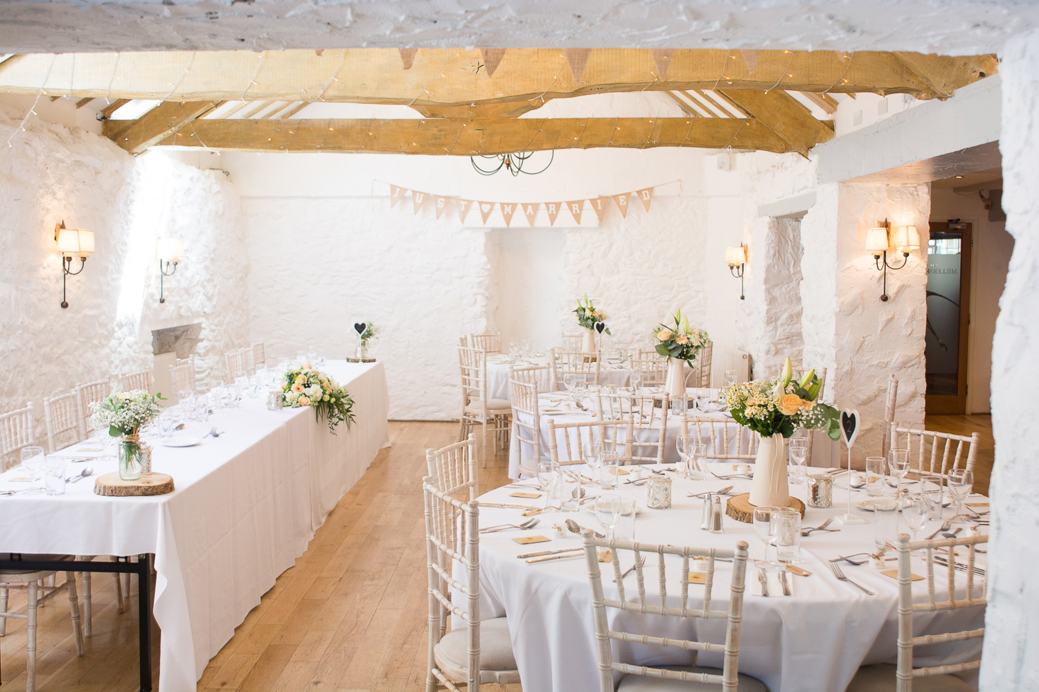 Exposed beams and tables set for the wedding breakfast at the wonderful Bickley Mill Wedding Venue in Devon