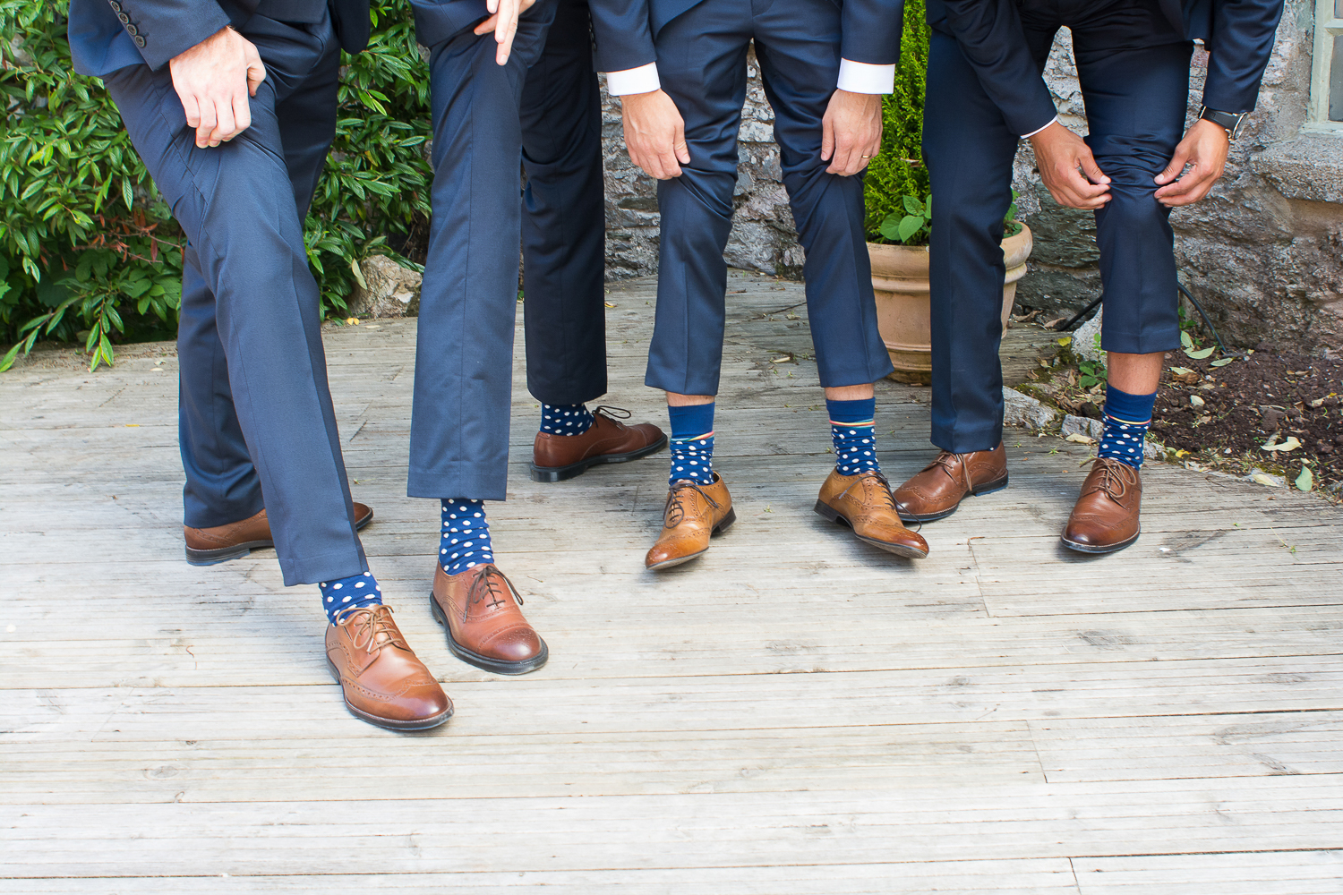 the groomsmen flash their matching sopotty socks on the decking at the Bickley Mill Wedding Venue in Devon