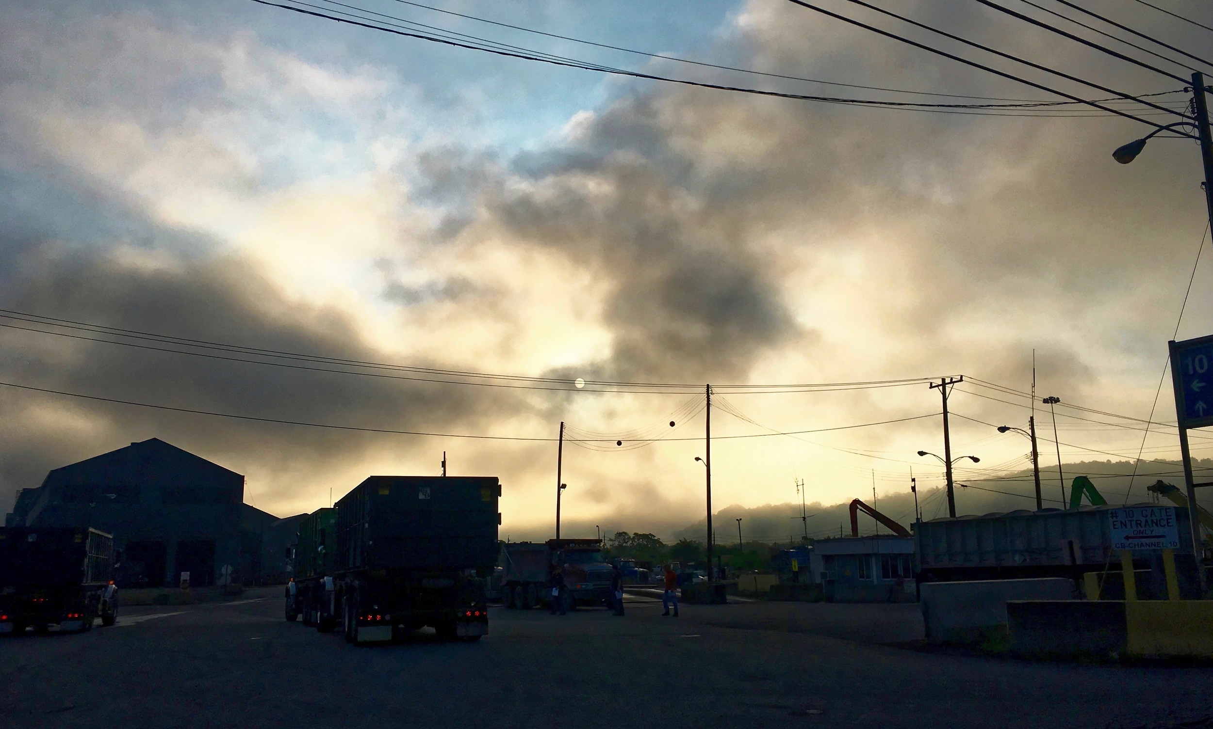 The sun rising over a scrap metal yard next to the Allegheny River. 