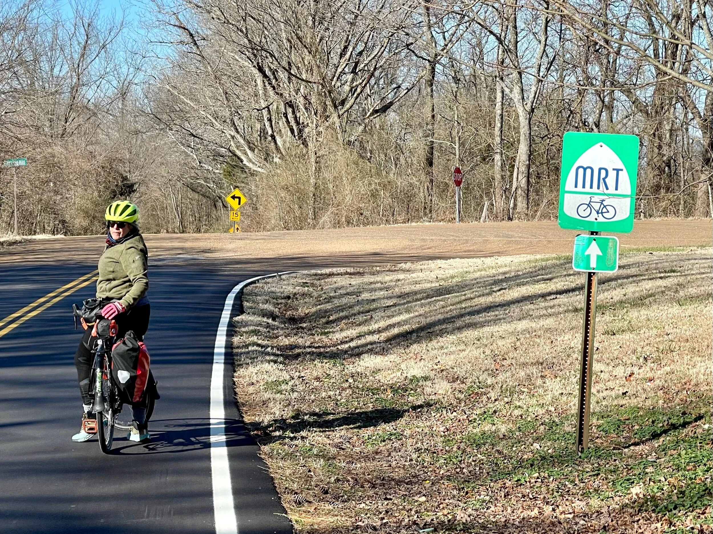 Jenny watches while I take a photo of the Mississippi River Trail (MRT ) sign about 20 miles north of Memphis. The Mississippi River Trail  (MRT) extends from Elk River, Minnesota to New Orleans, Louisiana. It is a conglomeration of roads that trave…
