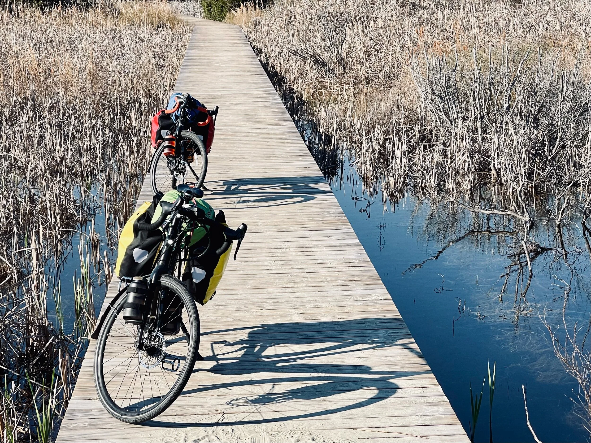 Our “fully loaded” Trek Crossrip e-bikes parked on a boardwalk near the beach on Sullivan Island in Charleston.