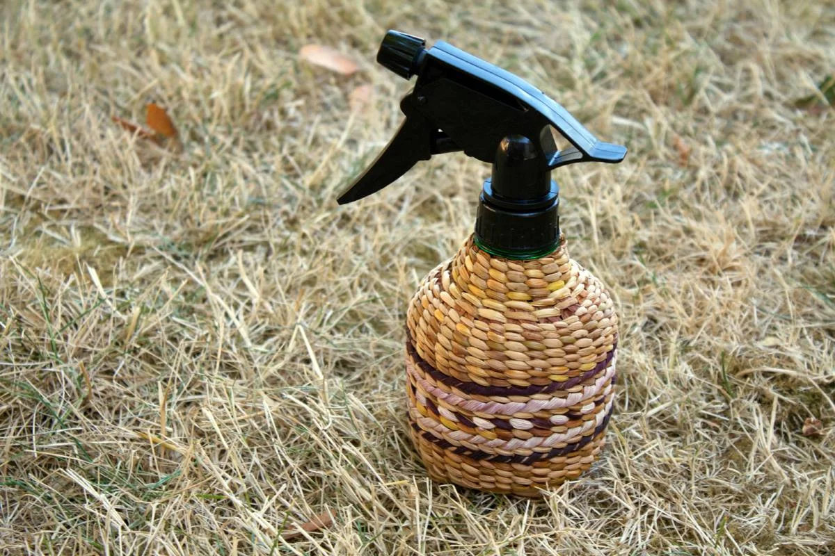 Western Red Cedar Bark and Sweet Grass Sedge Twined Spray Bottle Cover, with Red and White Corn Husk False Embroidery and Overlay. Woven under the instruction of the Ancient Arts Center.