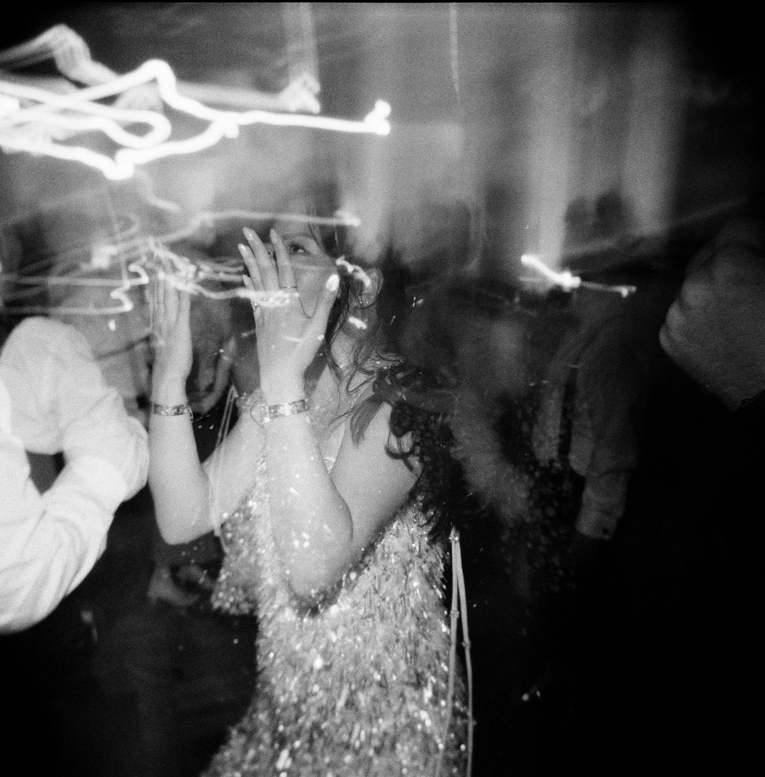 Black and white photo showing a bride dancing with light streaks, possibly indicating an electric or energetic scene. Photographed on a Holga 120.