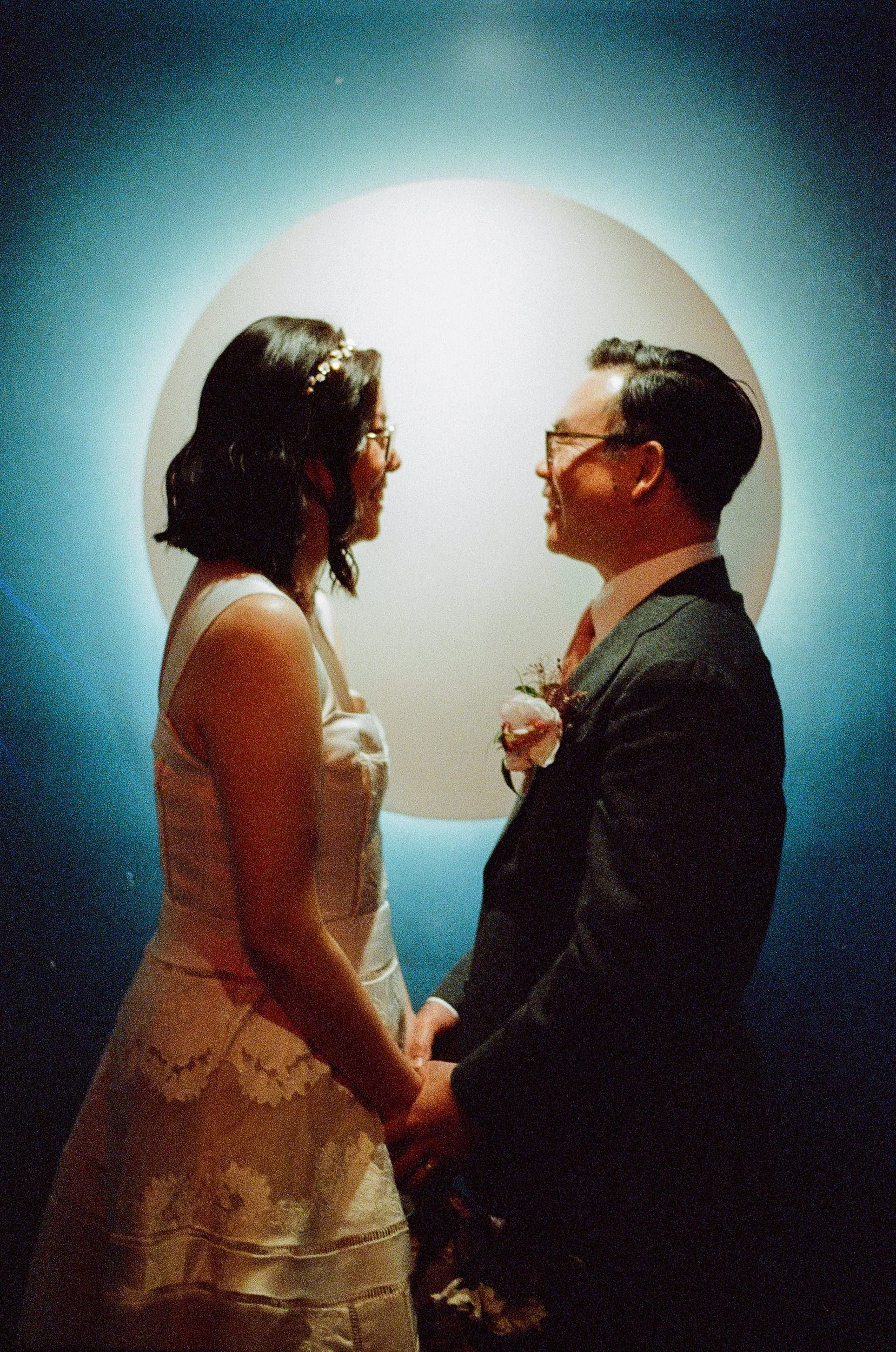 A bride and groom holding hands and gazing at each other in the hallway of the Moongate Lounge in San Francisco.