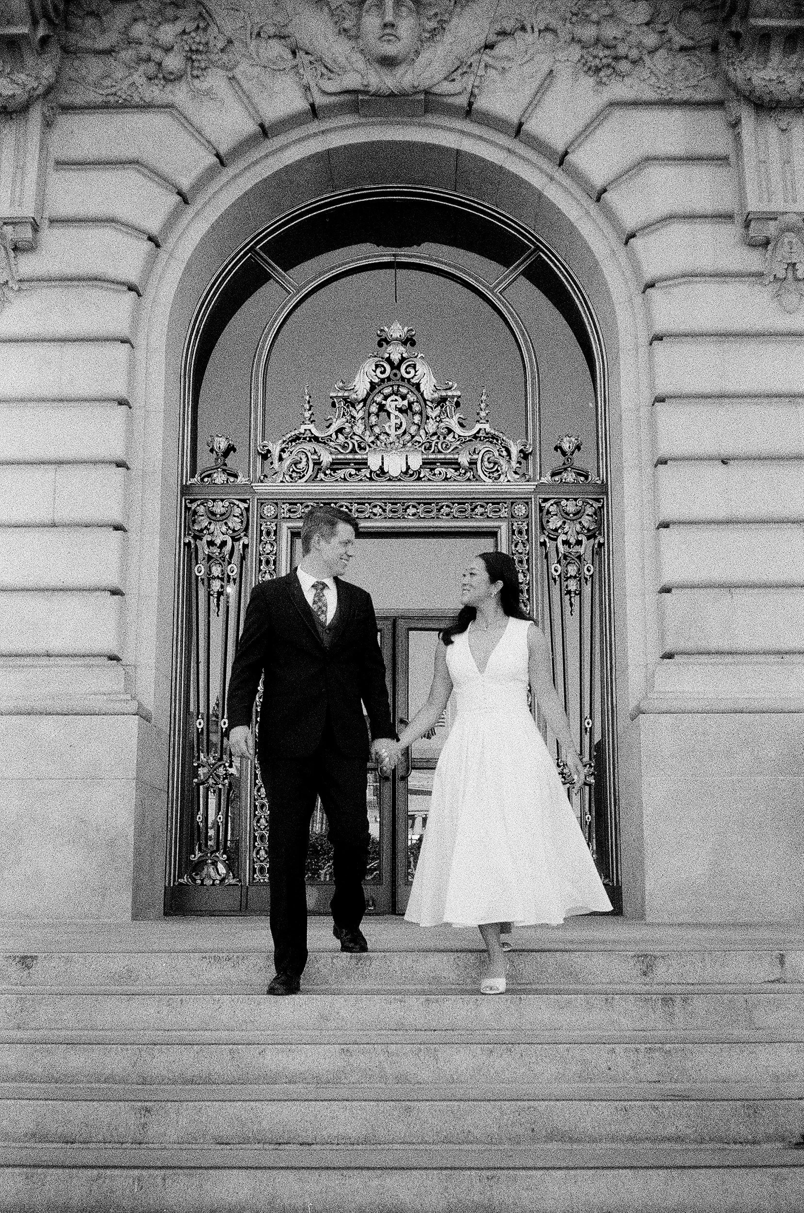 A couple walking outside of San Francisco City Hall shot on black and white film.