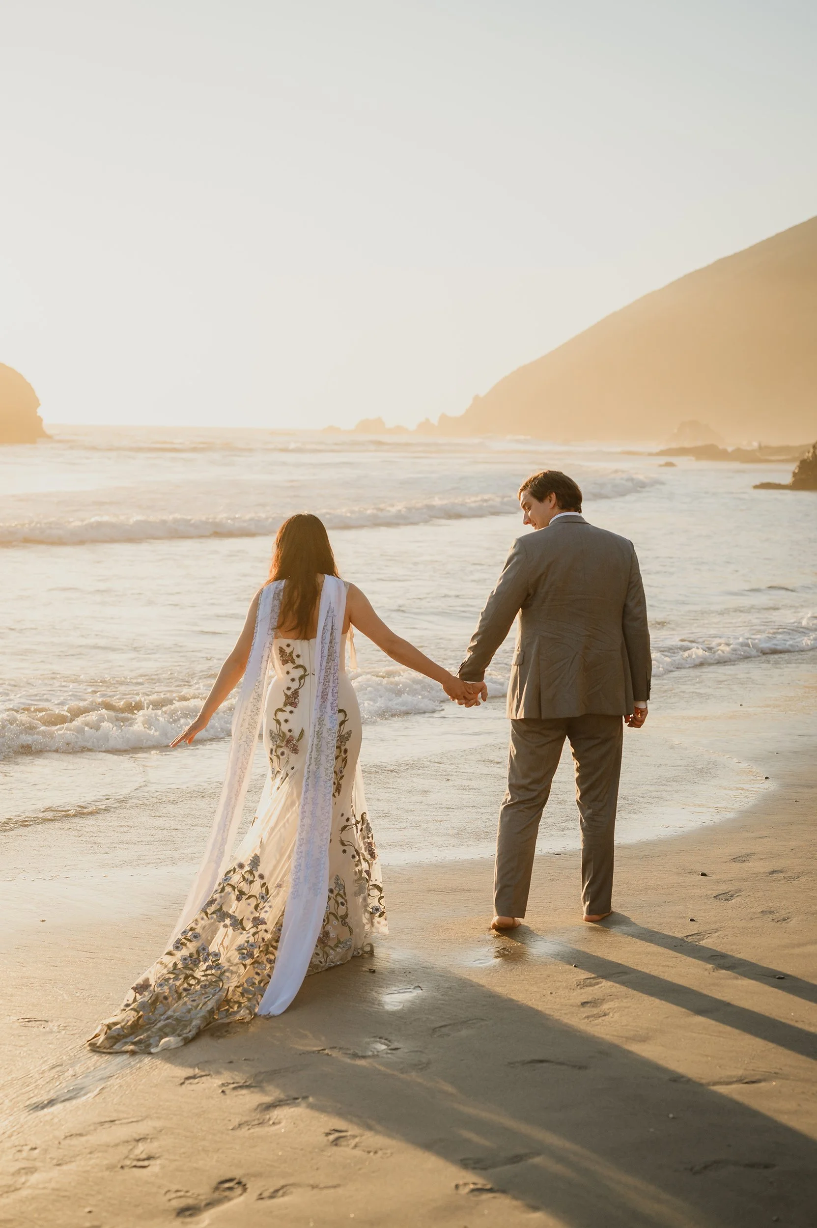 An elopement couple walking on Pfeiffer Beach in Big Sur at sunset.
