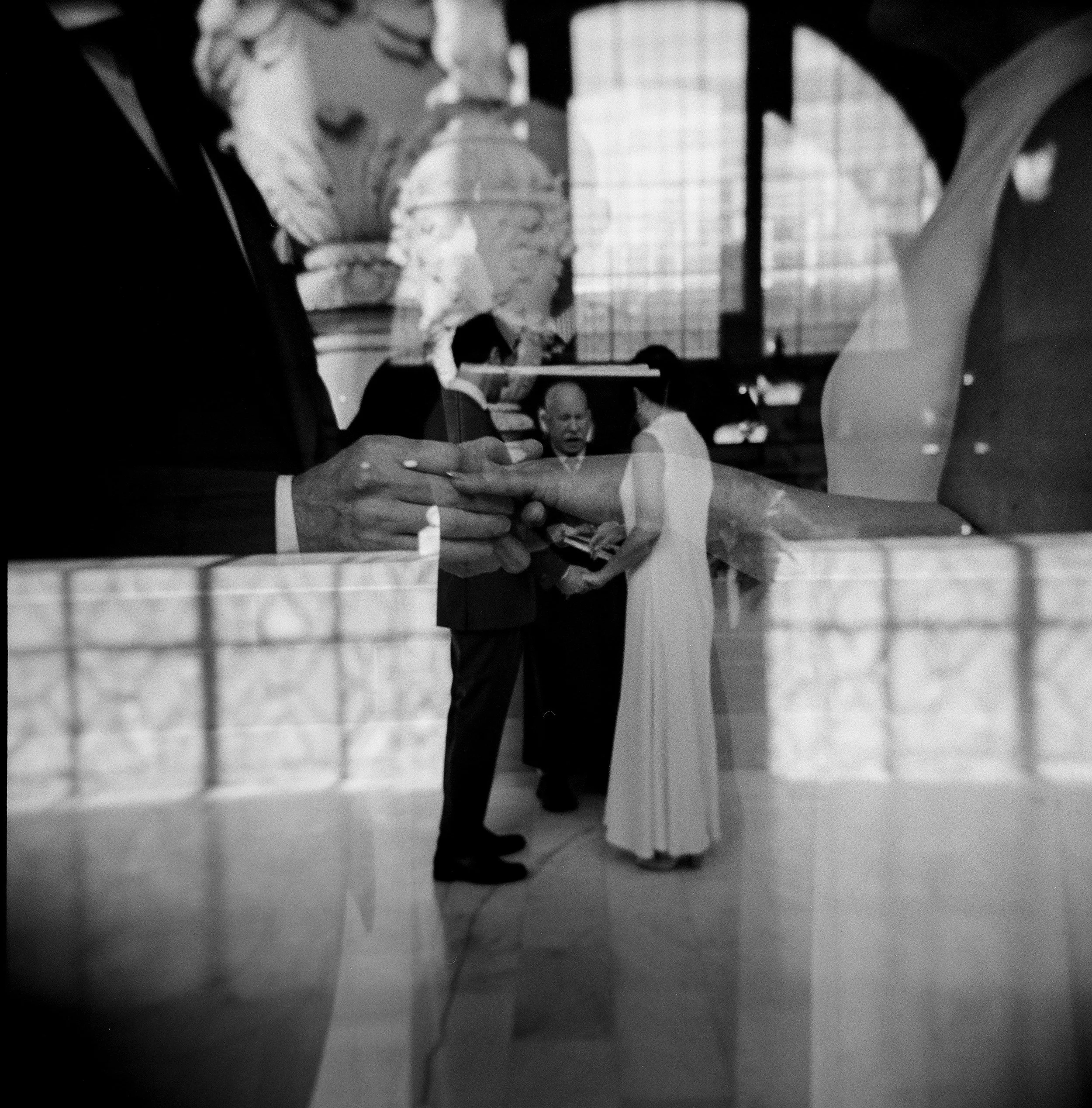 A black-and-white double exposure Holga film photograph of a couple getting married at SF City Hall.