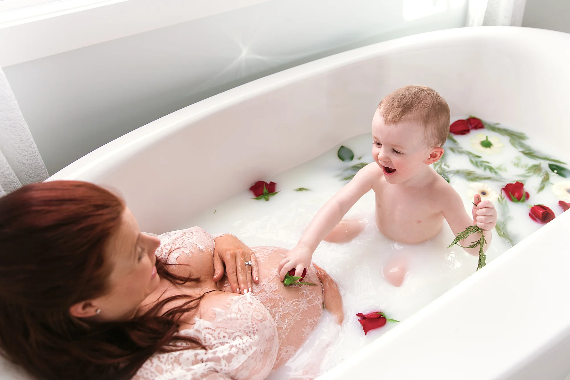 Mom-to-be and her toddler son are enjoying a milk bath during mom’s milk bath maternity photoshoot. Calgary Maternity Photographer - Milashka Photography