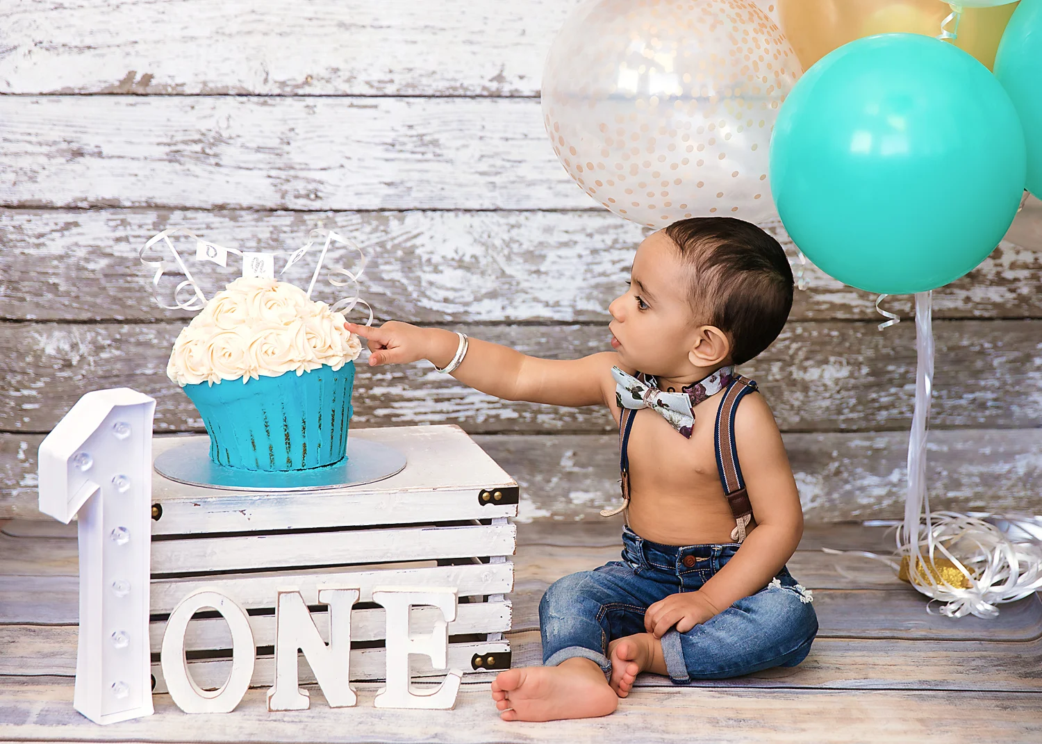 Little boy has his finger on his birthday cake - ready to taste the icing for the first time. Cakesmash photoshoot ideas. Calgary and Airdrie cakesmash and first birthday photographer.