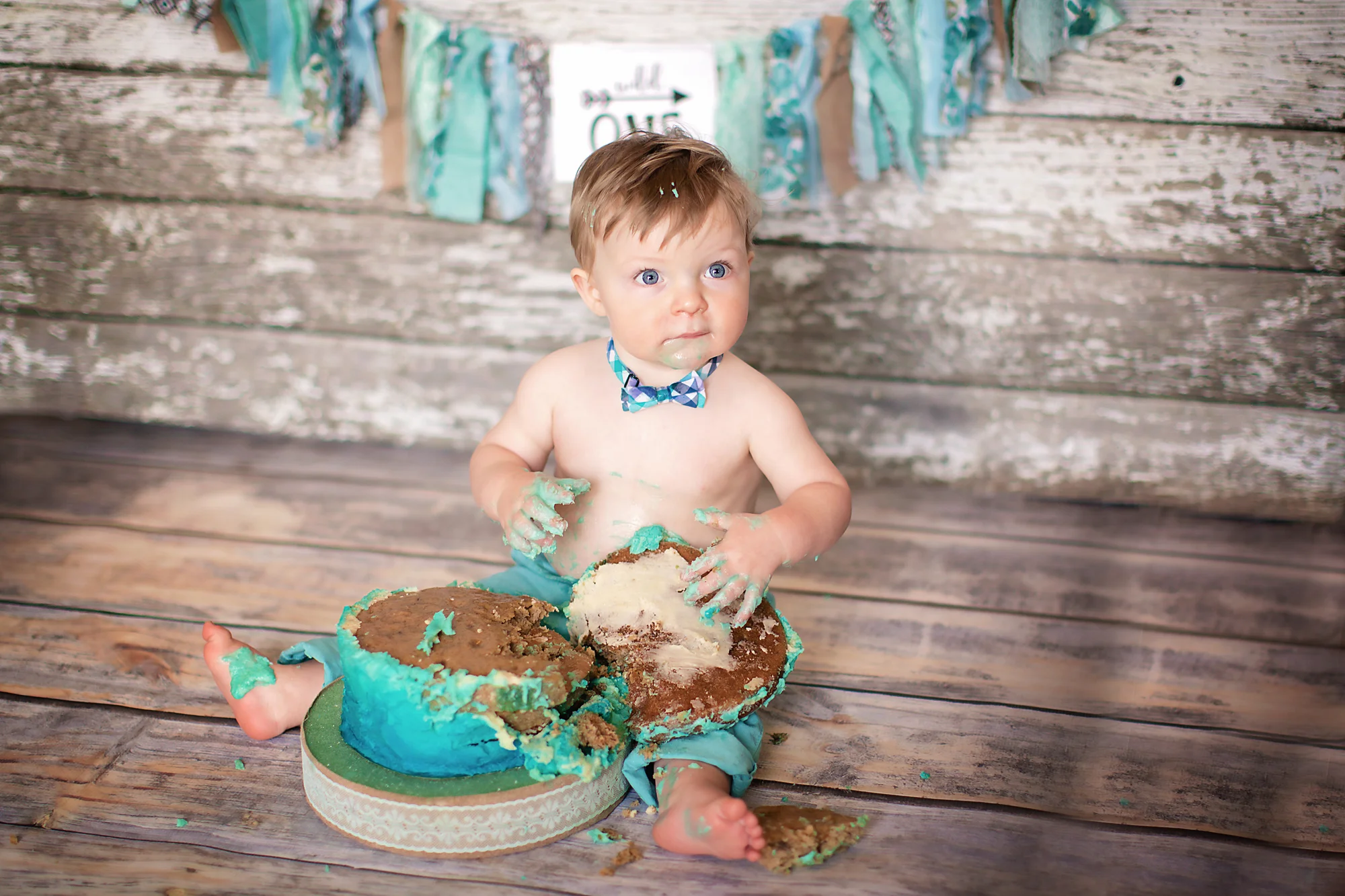 Little boy is completely destroying his birthday cake during his cakesmash photoshoot. Airdrie Cakesmash Photographer - Milashka Photography