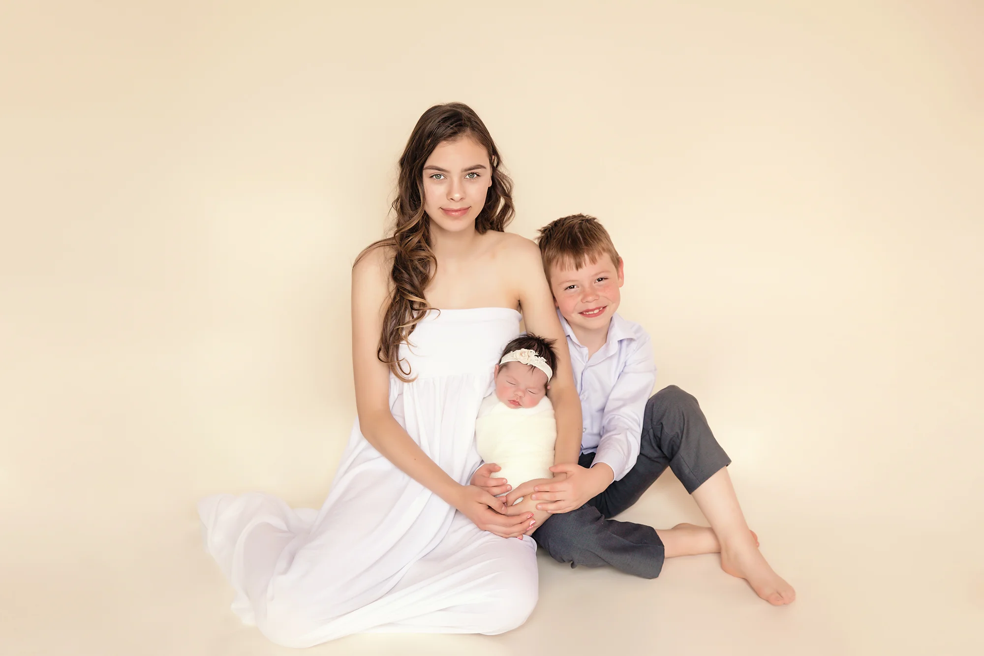 Newborn baby girl photoshoot idea. Calgary and Airdrie Newborn Photographer - Milashka Photography. Siblings are holding their newborn baby sister.