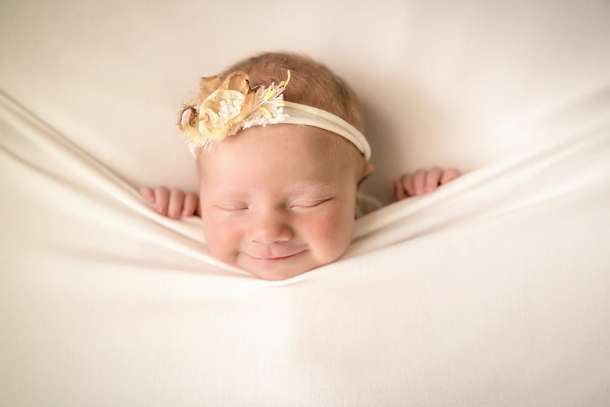 Newborn Photoshoot inspiration ideas. Calgary and Airdrie, Alberta Newborn and Baby photographer - Milashka Photography. Baby girl is smiling and is posed on a beanbag.
