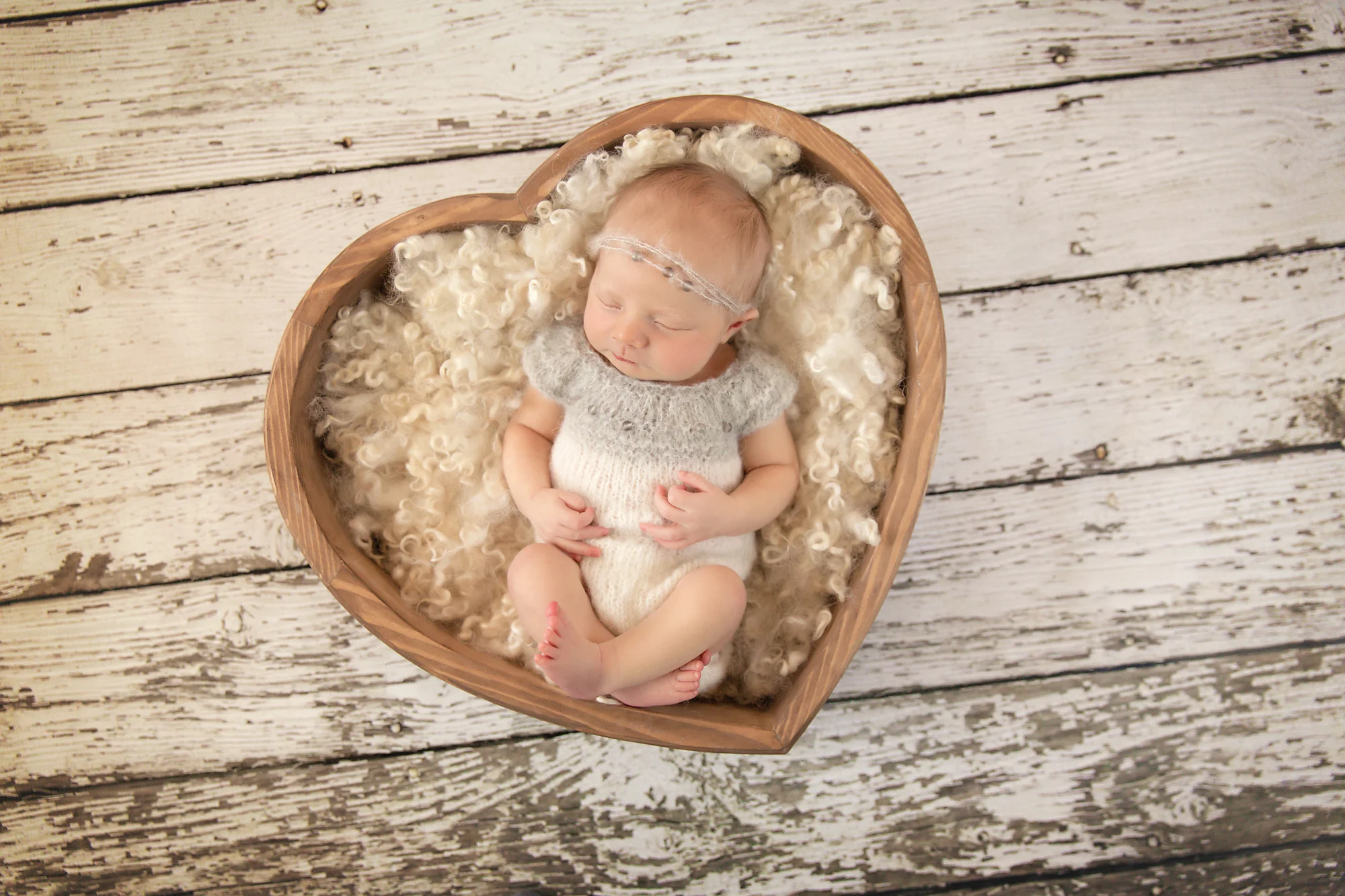Newborn Photoshoot inspiration ideas. Calgary and Airdrie, Alberta Newborn and Baby photographer - Milashka Photography. Baby girl is posed in a heart shaped wooden bowl and is wearing a cute little grey and white knitted outfit.